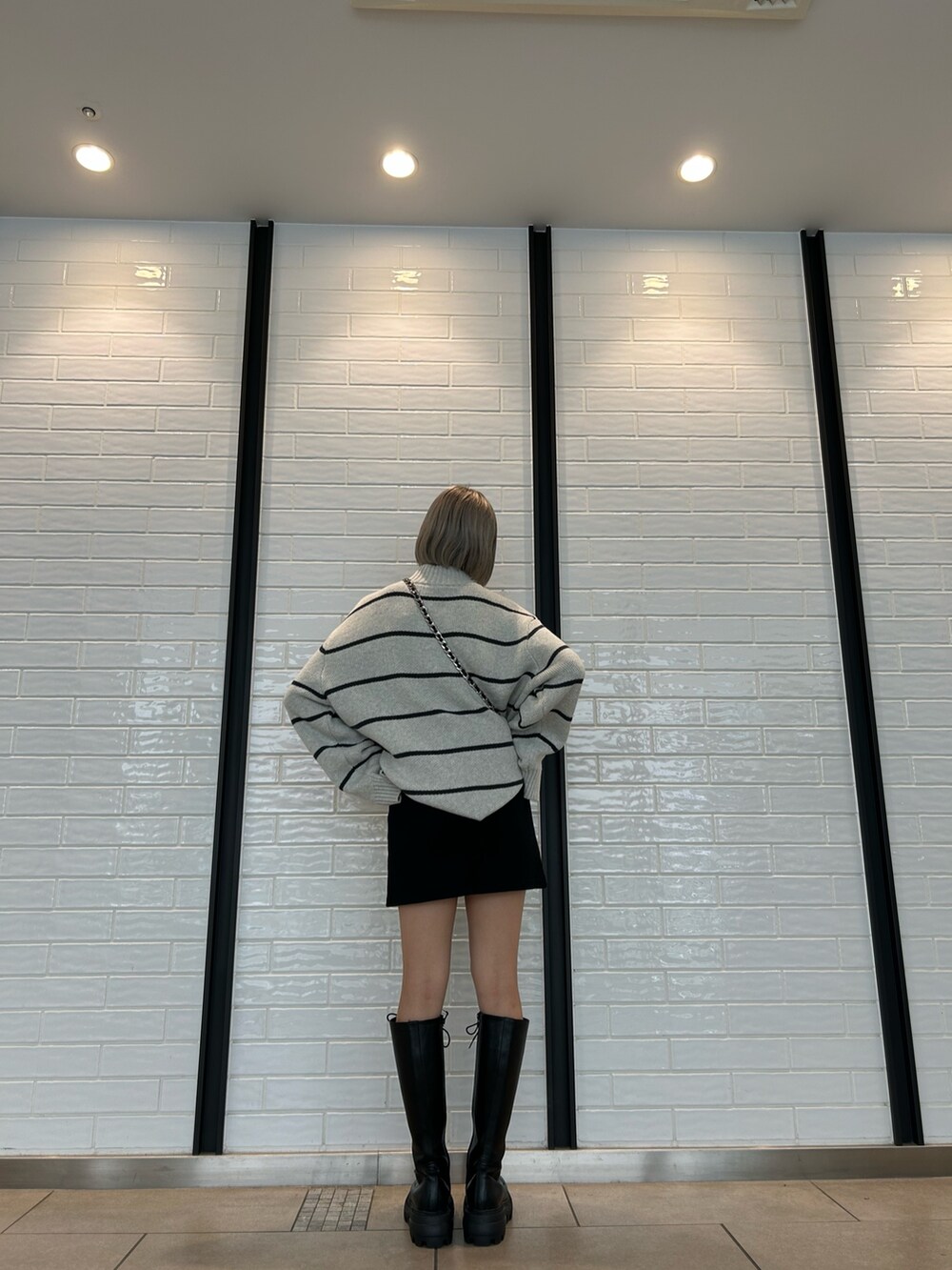 ブラック系のショルダーバッグ、ブラック系のスカート、ブラック系のブーツを着用したレディースの夏コーディネートの2枚目の写真