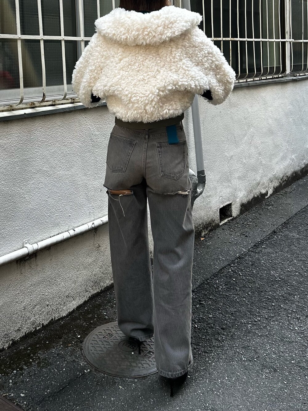 ブラック系のデニムパンツ、ホワイト系のブルゾン、ブルー系のTシャツ/カットソーを着用したレディースの秋コーディネートの2枚目の写真