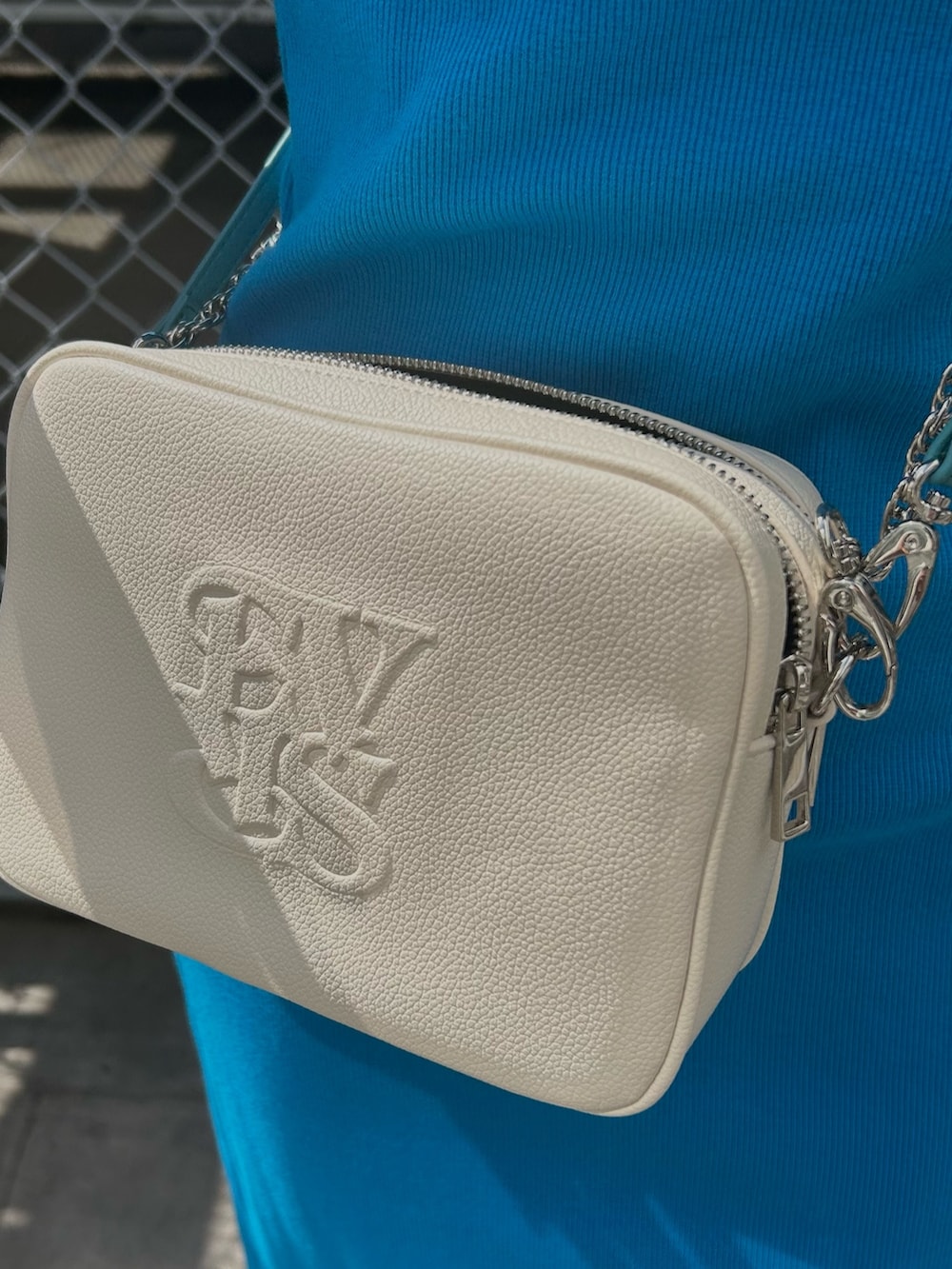 ブルー系のワンピース、ホワイト系のショルダーバッグ、ホワイト系のスニーカーを着用したレディースの春コーディネートの4枚目の写真