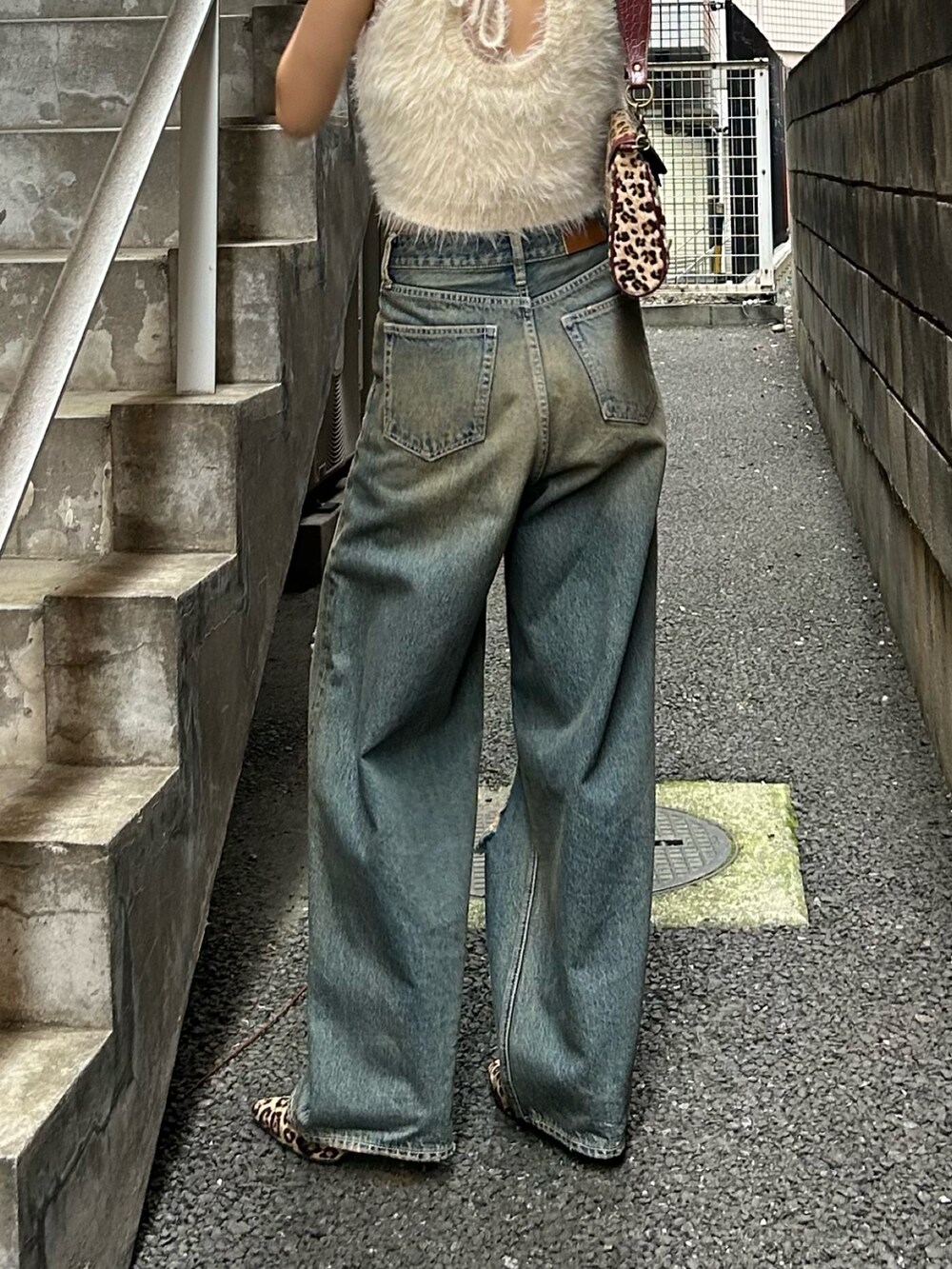 ブルー系のデニムパンツ、ホワイト系のタンクトップ、ベージュ系のハンドバッグを着用したレディースの夏コーディネートの2枚目の写真