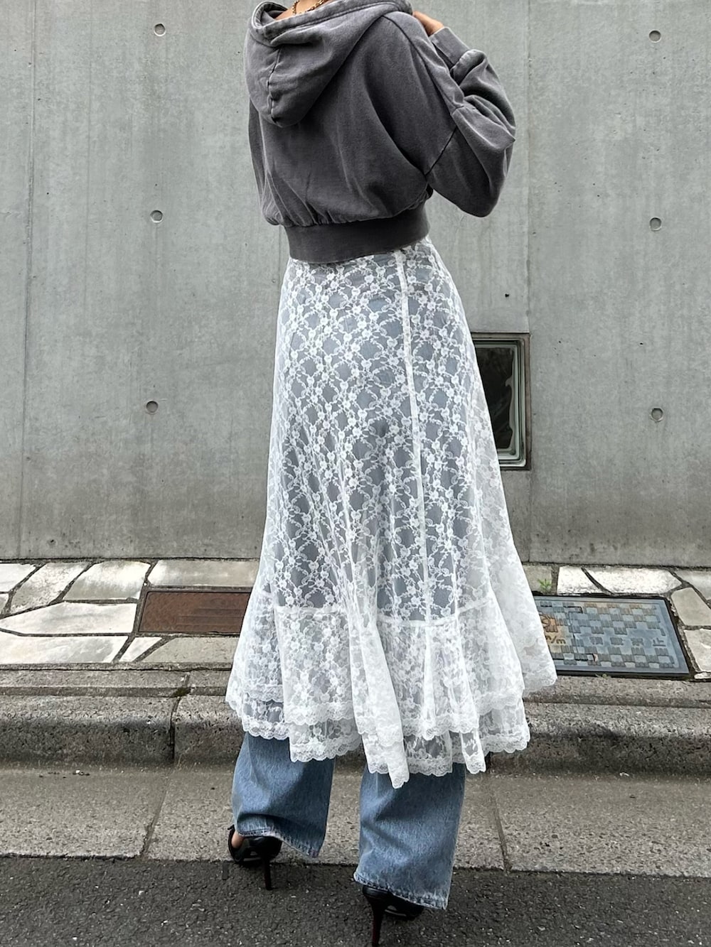 グレー系のスウェット、ホワイト系のスカート、ブルー系のデニムパンツを着用したレディースの夏コーディネートの2枚目の写真