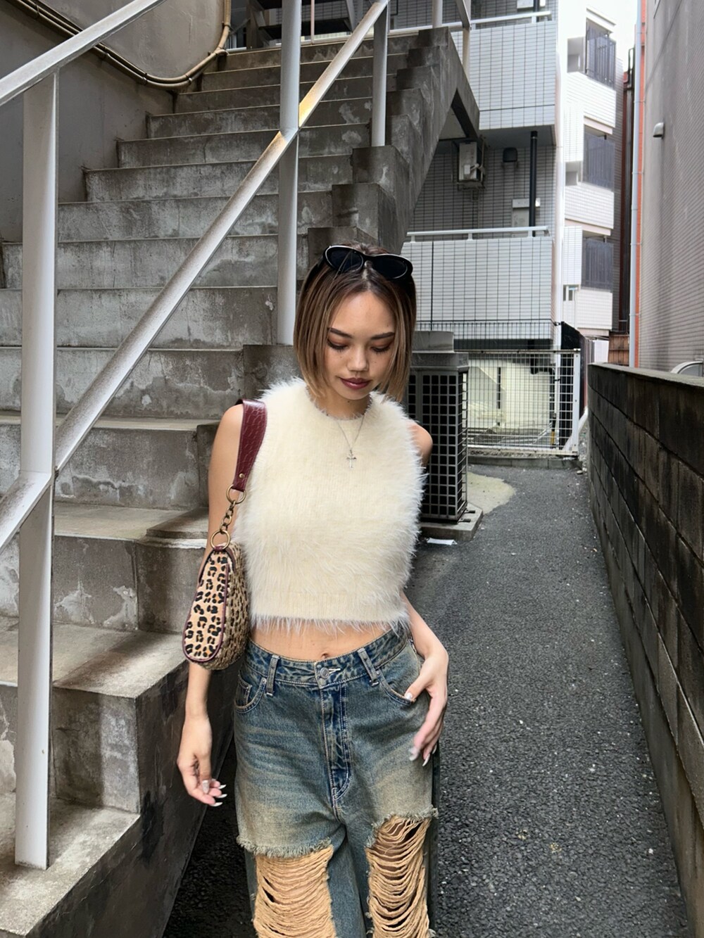 ブルー系のデニムパンツ、ホワイト系のタンクトップ、ベージュ系のハンドバッグを着用したレディースの夏コーディネートの3枚目の写真