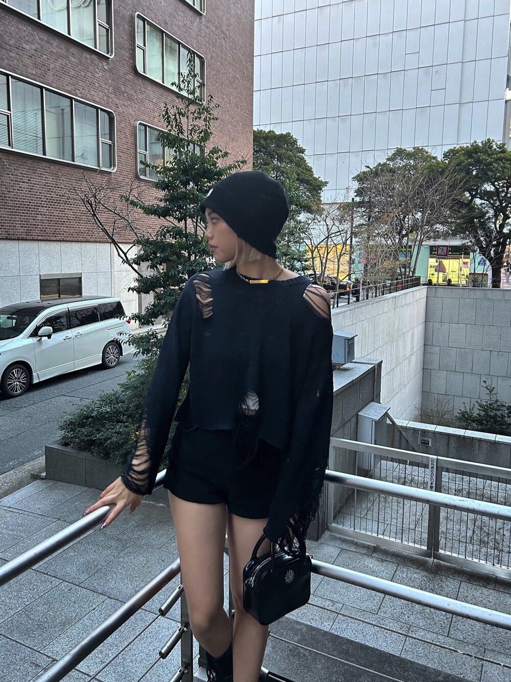 ブラック系のショルダーバッグ、ブラック系のニット/セーター、ブラック系のブーツを着用したレディースの春コーディネートの2枚目の写真