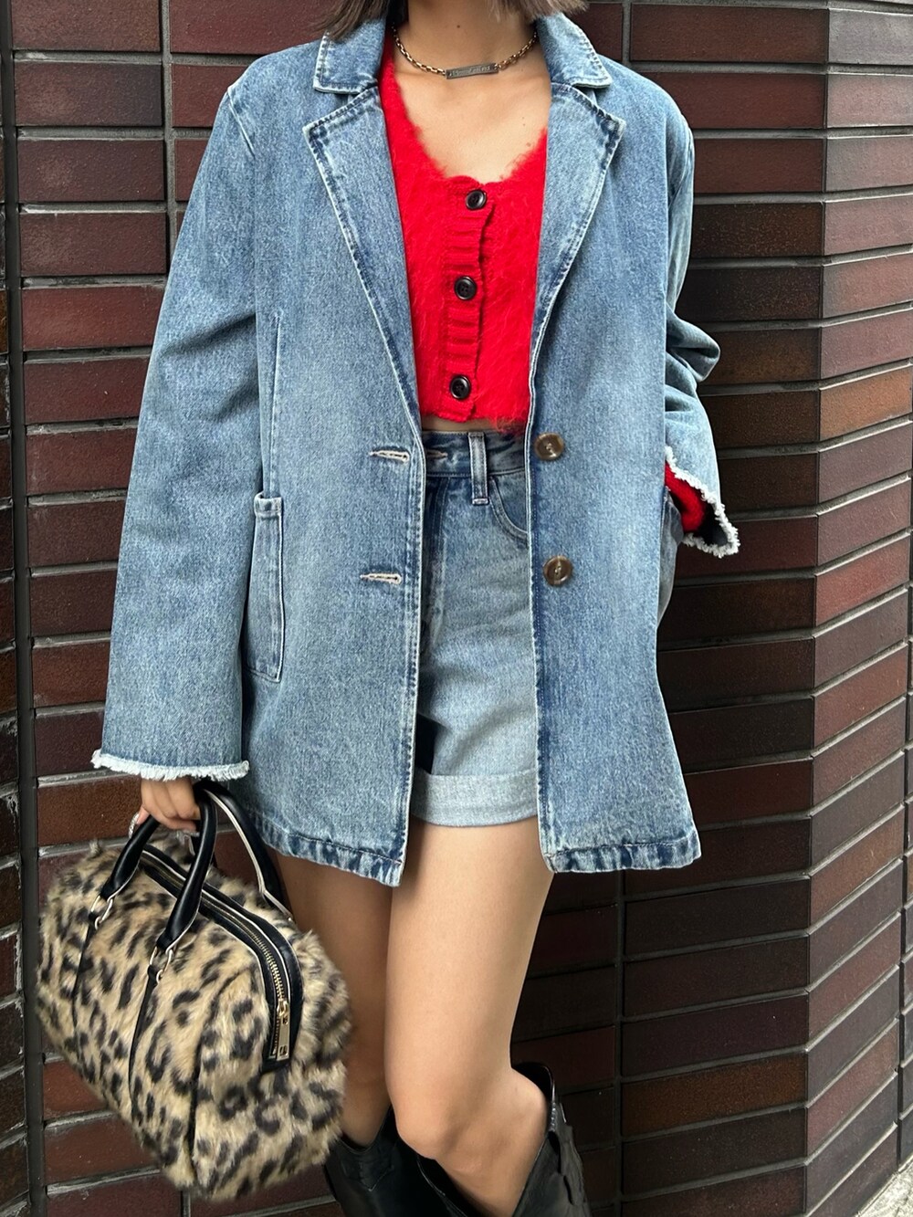 レッド系のニット/セーター、ブルー系のデニムジャケット、ブルー系のデニムパンツを着用したレディースの夏コーディネートの3枚目の写真