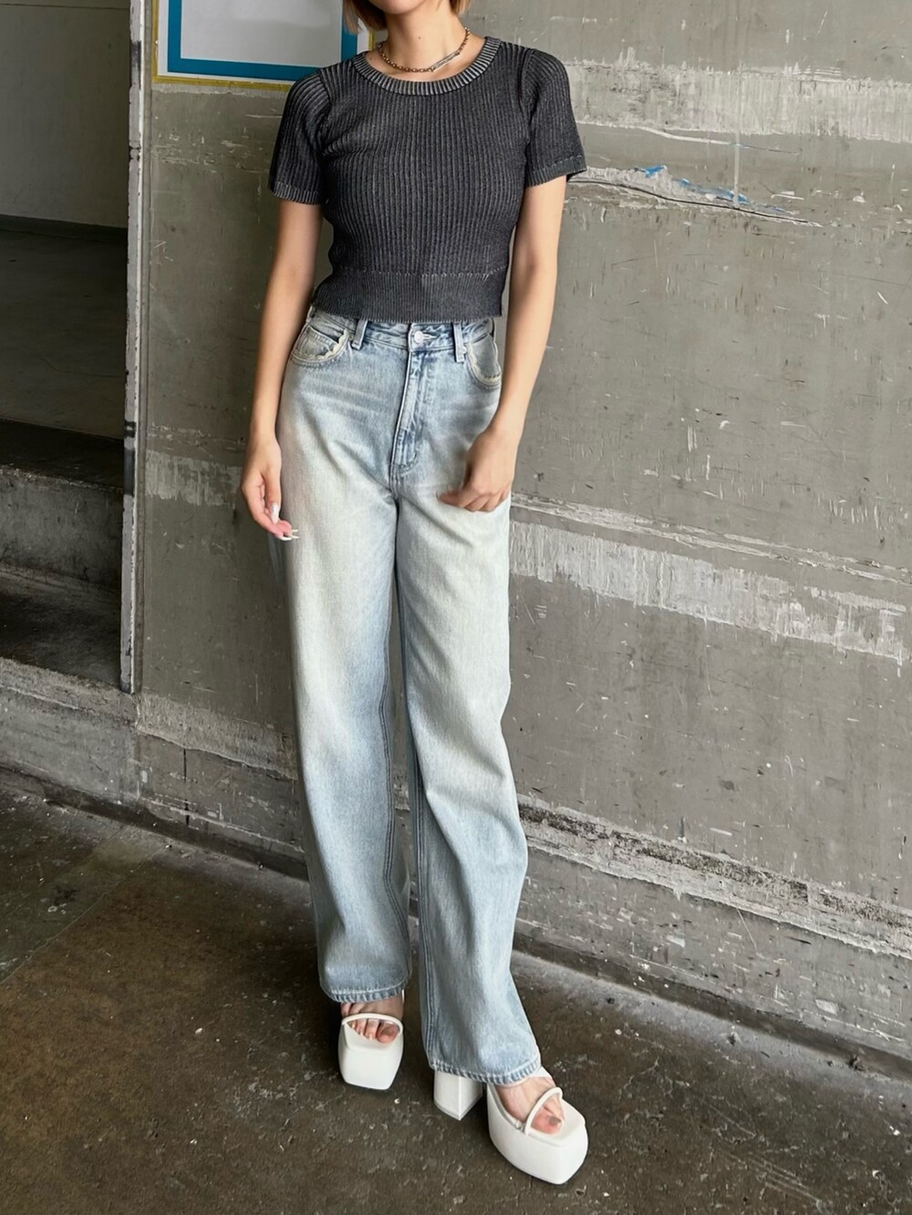 ブルー系のデニムパンツ、ブラック系のニット/セーター、ホワイト系のサンダルを着用したレディースの夏コーディネートの2枚目の写真