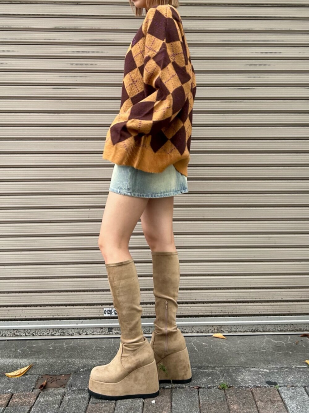 ブルー系のデニムスカート、ブラウン系のニット/セーター、ベージュ系のブーツを着用したレディースの秋コーディネートの2枚目の写真