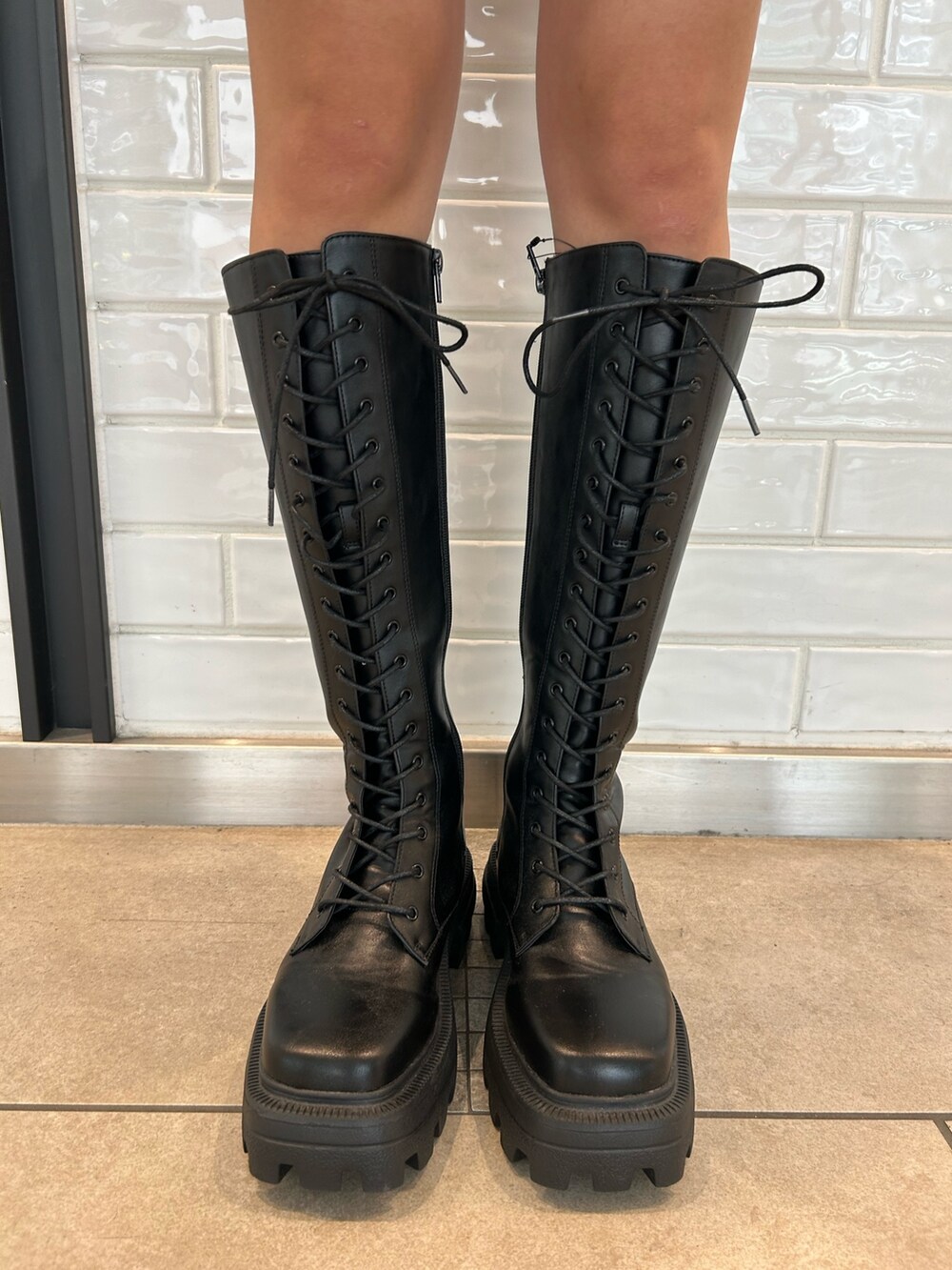 ブラック系のショルダーバッグ、ブラック系のスカート、ブラック系のブーツを着用したレディースの夏コーディネートの6枚目の写真