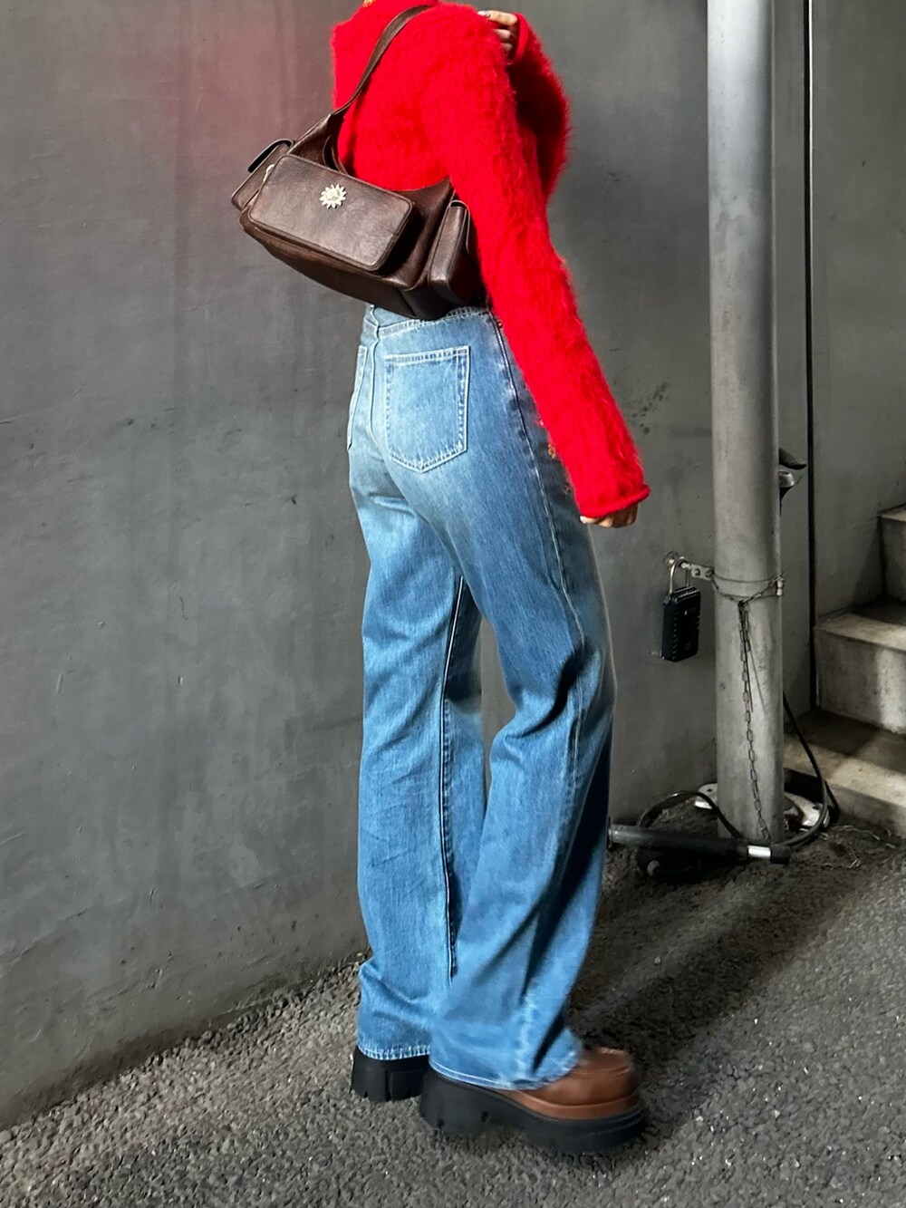 レッド系のニット/セーター、ブルー系のデニムパンツ、ブラウン系のハンドバッグを着用したレディースの夏コーディネートの3枚目の写真