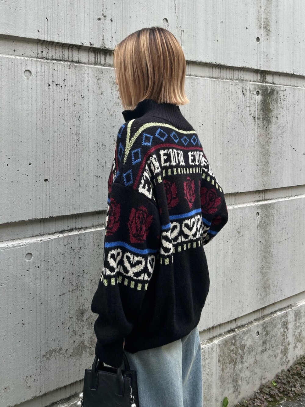 ブラック系のショルダーバッグ、ブラック系のニット/セーター、ブルー系のデニムパンツを着用したレディースの秋コーディネートの5枚目の写真