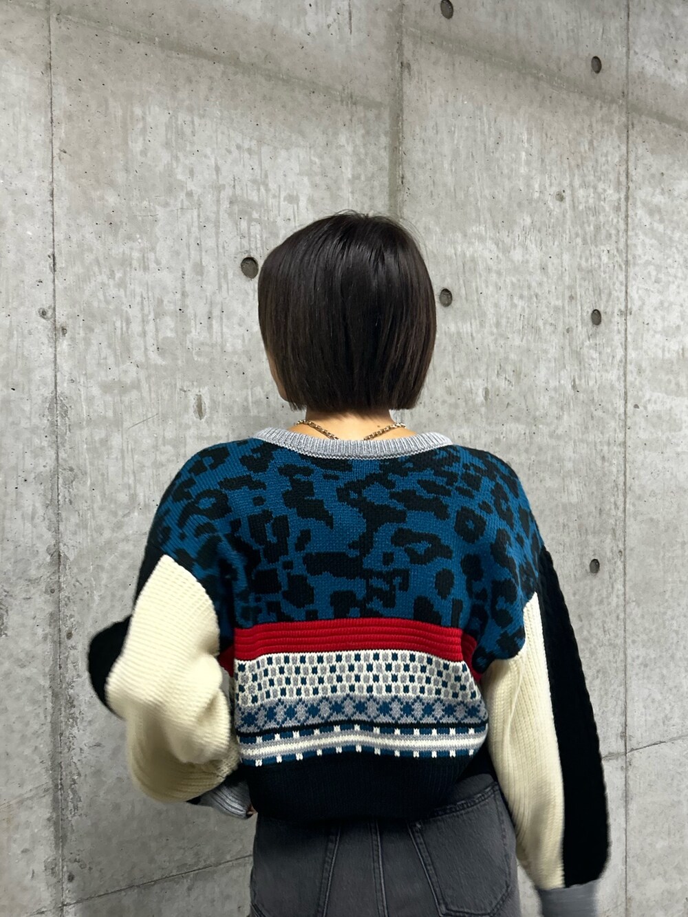 ブルー系のニット/セーター、ブラック系のデニムパンツ、ブラック系のローファーを着用したレディースの秋コーディネートの3枚目の写真