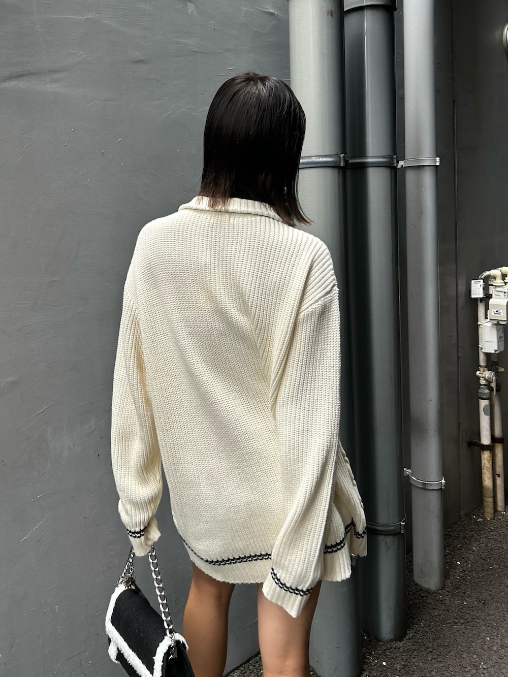 ホワイト系のニット/セーター、ブラック系のブーツ、ブラック系のショルダーバッグを着用したレディースの夏コーディネートの4枚目の写真