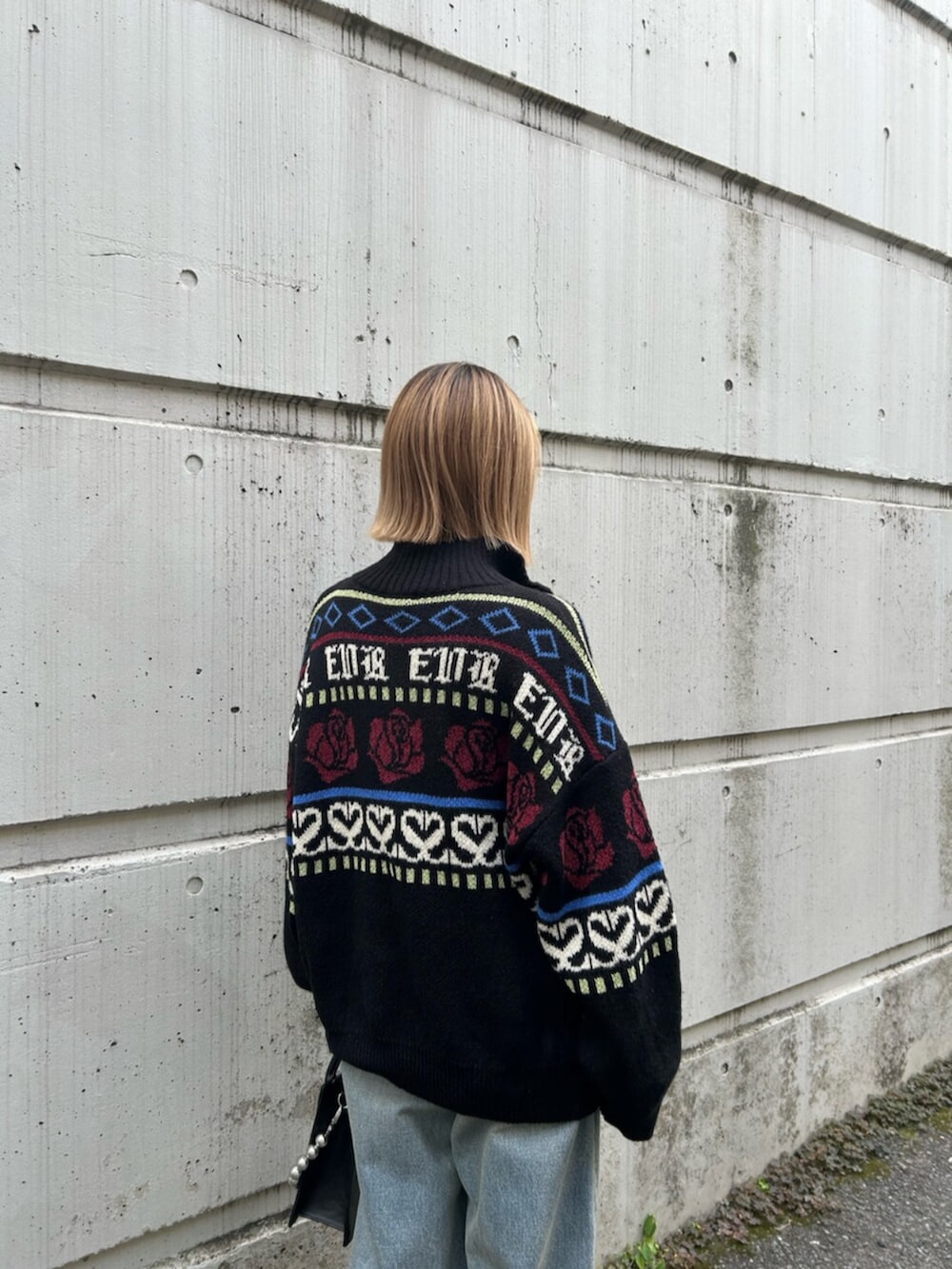 ブラック系のショルダーバッグ、ブラック系のニット/セーター、ブルー系のデニムパンツを着用したレディースの秋コーディネートの6枚目の写真