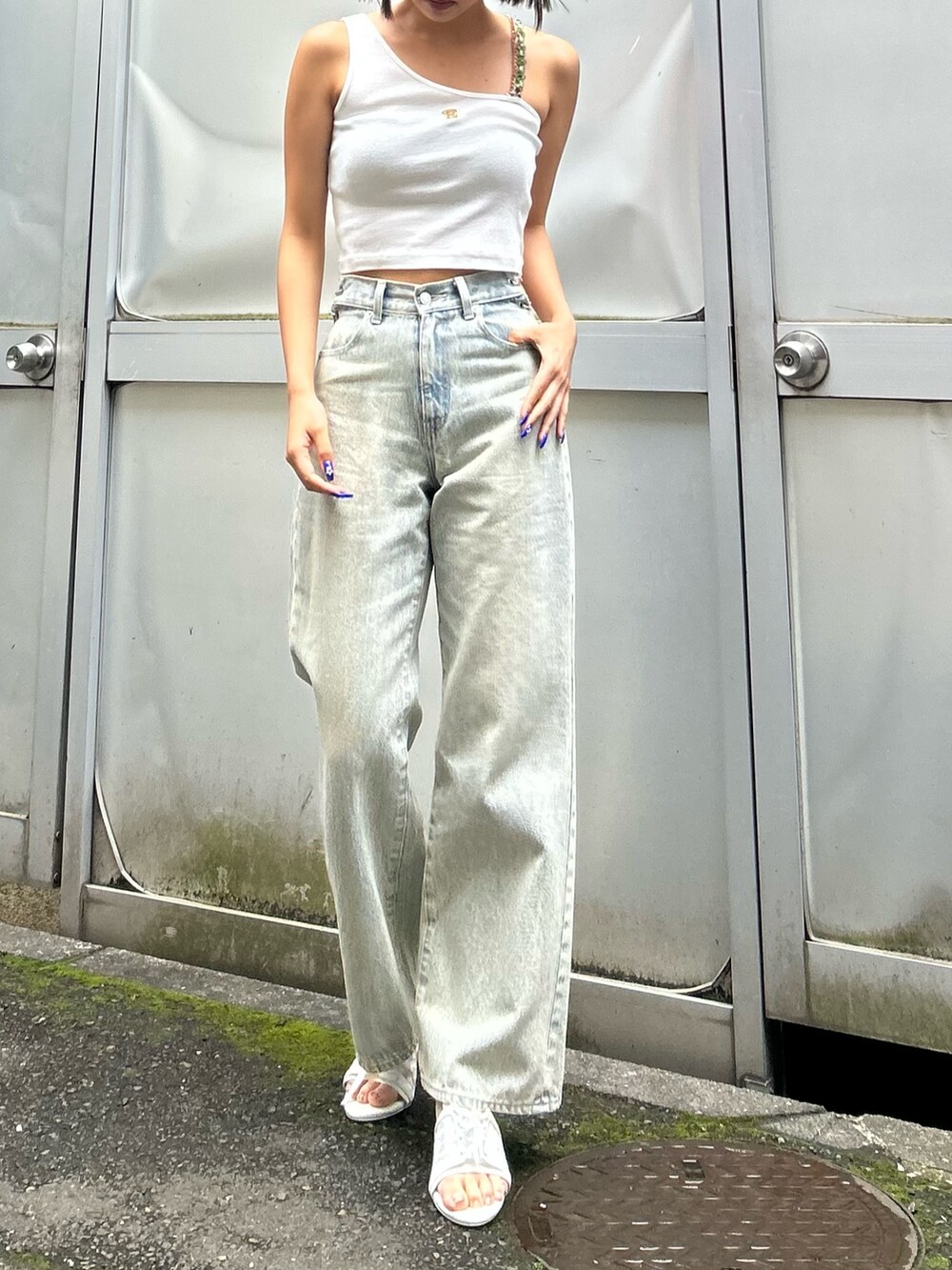 ブルー系のデニムパンツ、ホワイト系のタンクトップ、ホワイト系のサンダルを着用したレディースの春コーディネートの3枚目の写真