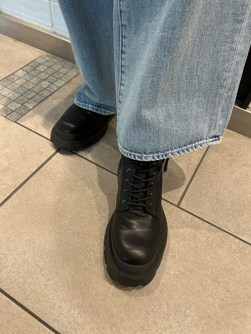 ブルー系のデニムパンツ、グリーン系のテーラードジャケット、ブラック系のハンドバッグを着用したレディースの秋コーディネートの4枚目の写真