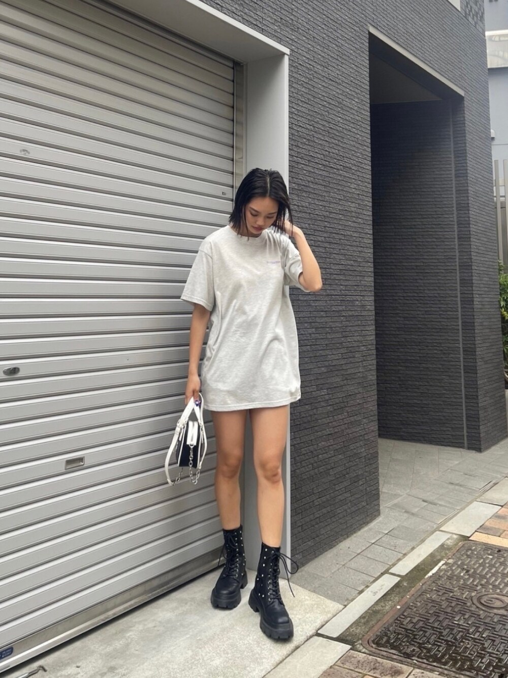 グレー系のTシャツ/カットソー、ブラック系のブーツ、ブラック系のショルダーバッグを着用したレディースの夏コーディネートの2枚目の写真