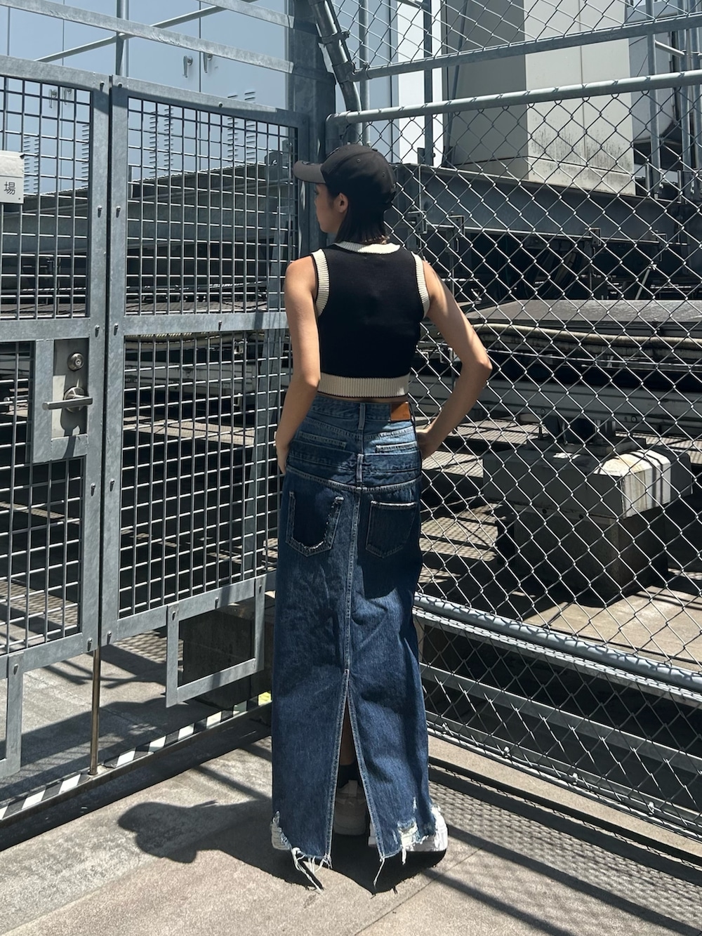 ブルー系のデニムスカート、ブラック系のベストを着用したレディースの春コーディネートの2枚目の写真