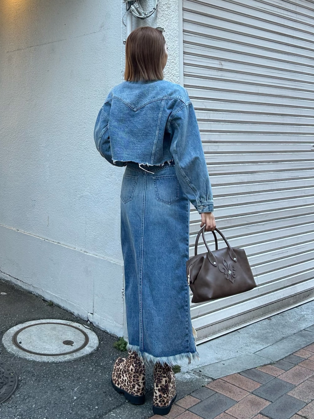 ブルー系のデニムスカート、ブルー系のデニムジャケット、ホワイト系のTシャツ/カットソーを着用したレディースの春コーディネートの3枚目の写真