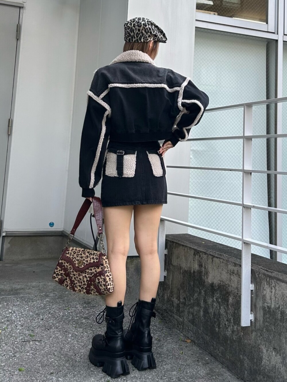 ブラック系のブルゾン、ブラック系のデニムスカート、ベージュ系のハンドバッグを着用したレディースの秋コーディネートの2枚目の写真