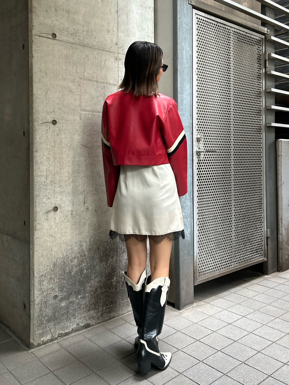 レッド系のライダースジャケット、ホワイト系のワンピース、その他のブーツを着用したレディースの夏コーディネートの2枚目の写真