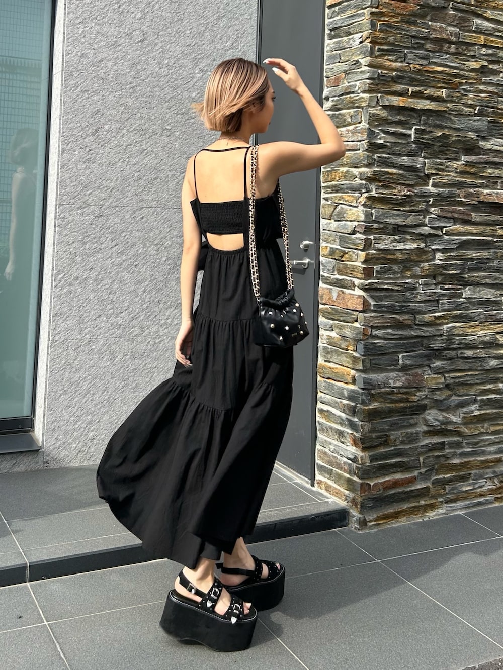 ブラック系のワンピース、ブラック系のショルダーバッグ、ブラック系のサンダルを着用したレディースの夏コーディネートの2枚目の写真