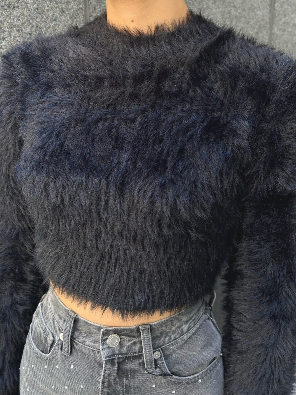 ブラック系のニット/セーター、ブラック系のデニムパンツ、ブラック系のハンドバッグを着用したレディースの秋コーディネートの4枚目の写真