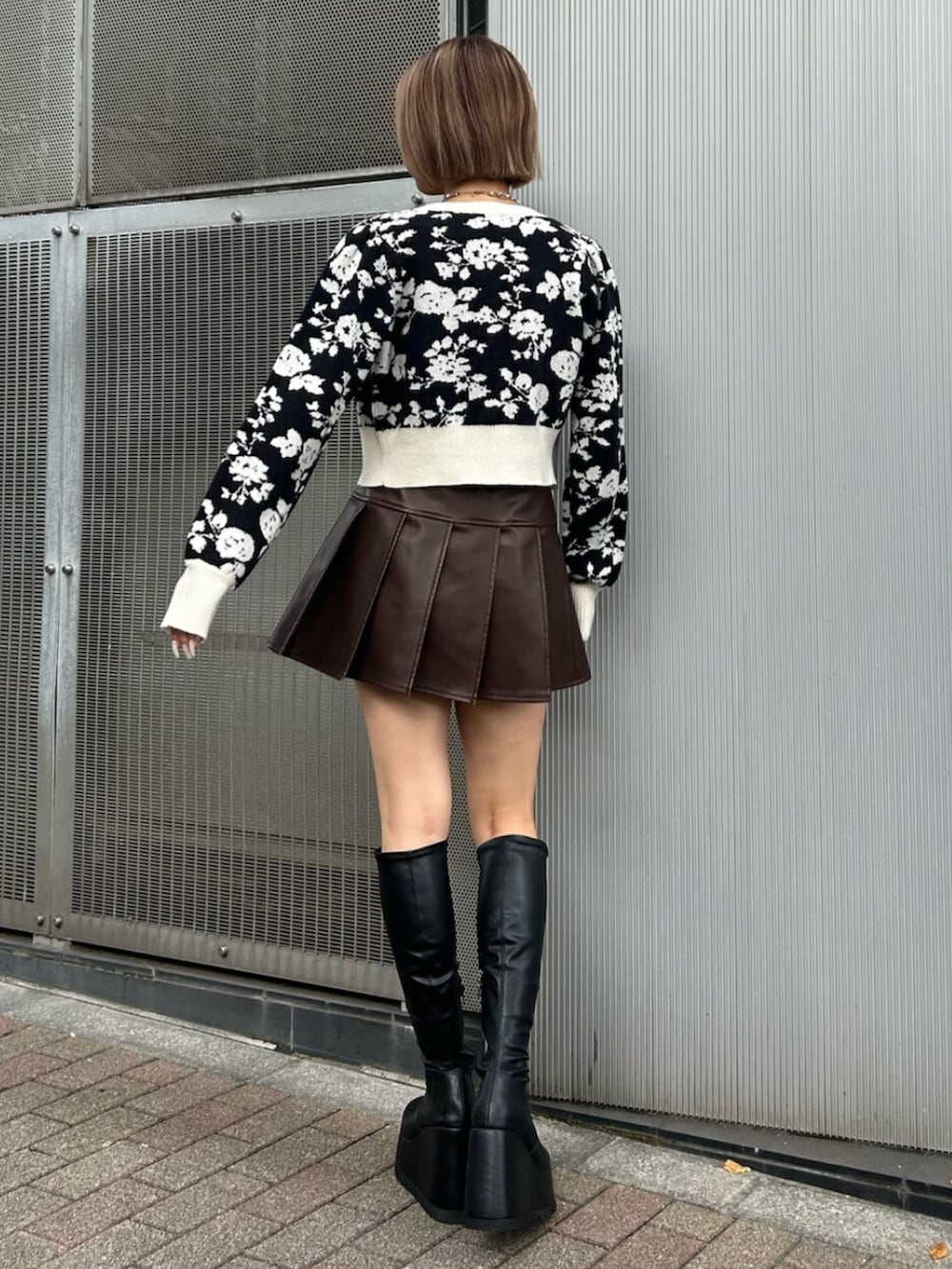 ブラック系のブーツ、ブラック系のニット/セーター、ブラウン系のスカートを着用したレディースの秋コーディネートの2枚目の写真