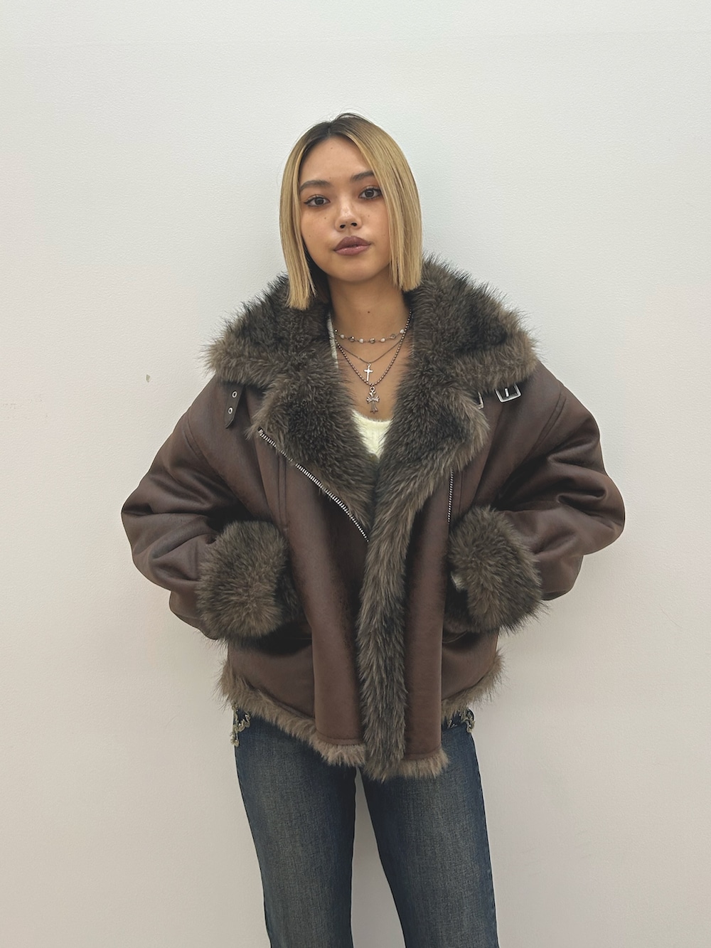 ブラウン系のブルゾン、ホワイト系のニット/セーター、ブルー系のデニムパンツを着用したレディースの秋コーディネートの4枚目の写真