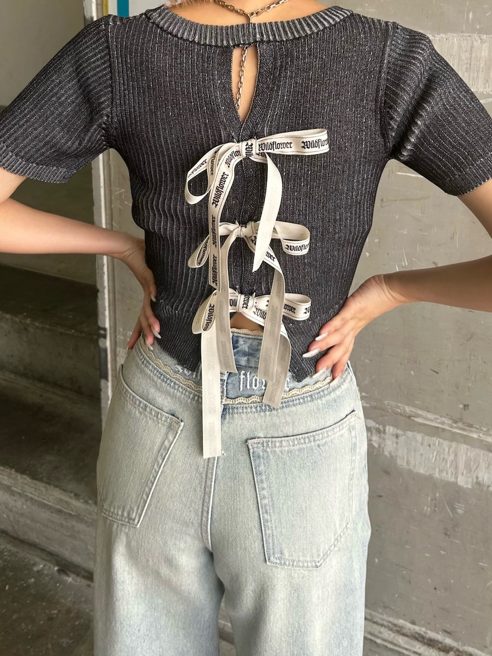 ブルー系のデニムパンツ、ブラック系のニット/セーター、ホワイト系のサンダルを着用したレディースの夏コーディネートの3枚目の写真