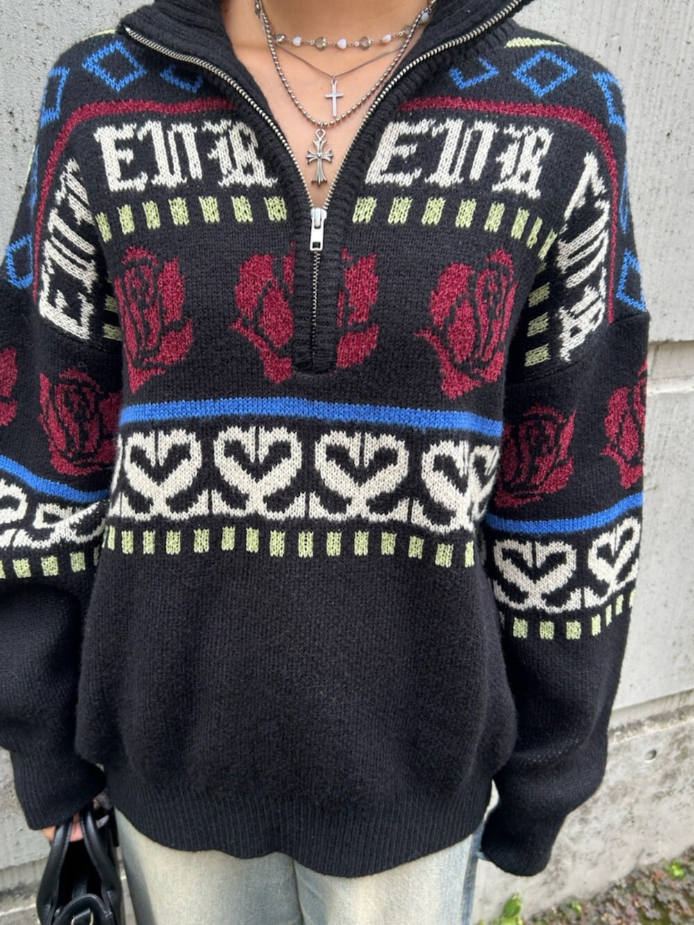 ブラック系のショルダーバッグ、ブラック系のニット/セーター、ブルー系のデニムパンツを着用したレディースの秋コーディネートの7枚目の写真