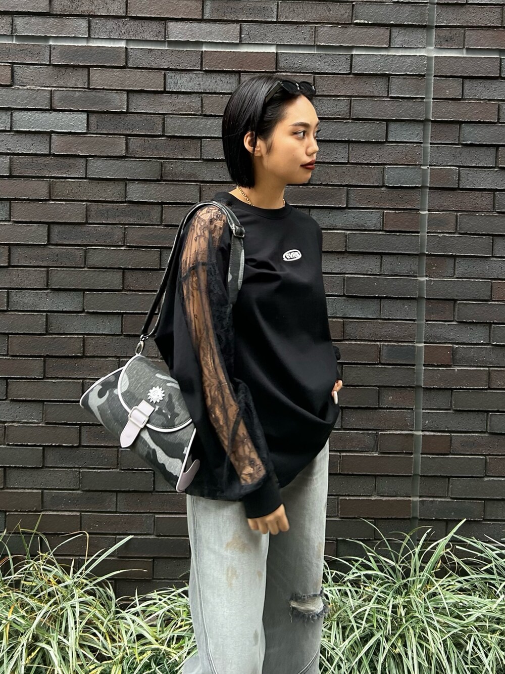 ブラック系のデニムパンツ、ブラック系のTシャツ/カットソー、グリーン系のサンダルを着用したレディースの冬コーディネートの3枚目の写真