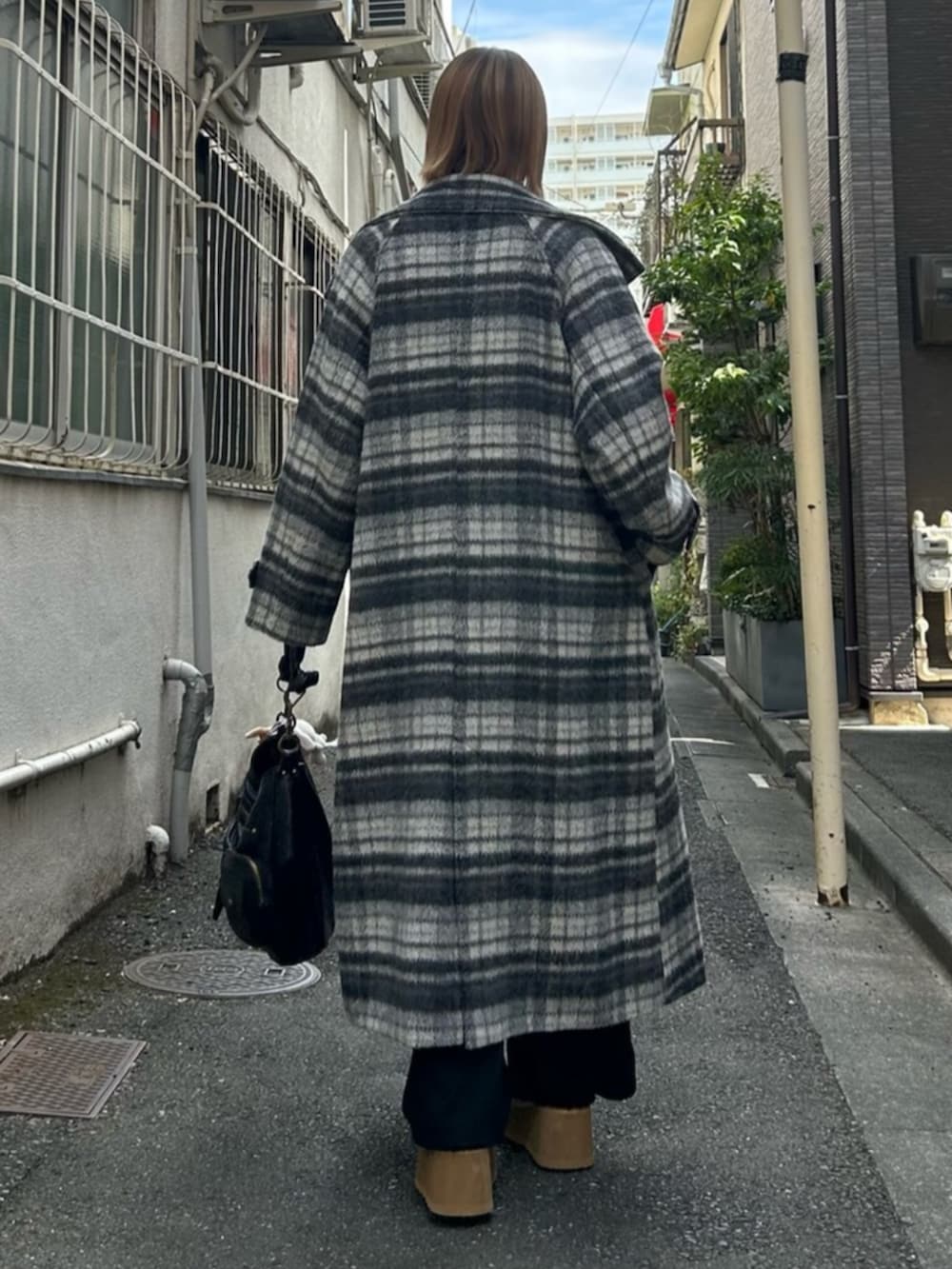 ブラック系のハンドバッグ、ブラック系のスリッポン、グレー系のチェスターコートを着用したレディースの秋コーディネートの3枚目の写真