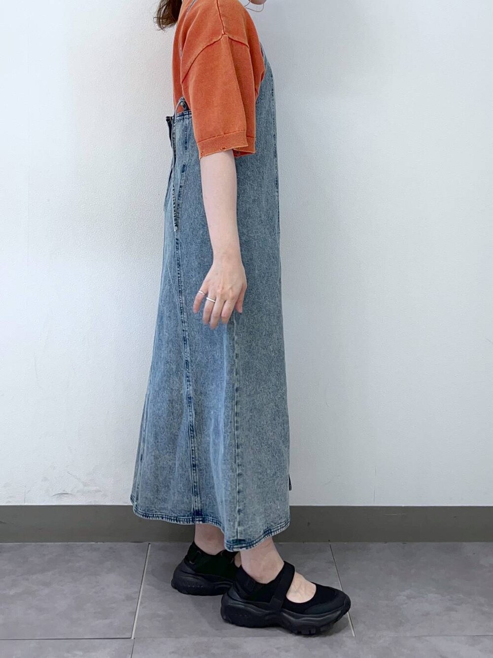 ブラック系のスニーカー、ブルー系のワンピース、オレンジ系のTシャツ/カットソーを着用したレディースの夏コーディネートの2枚目の写真