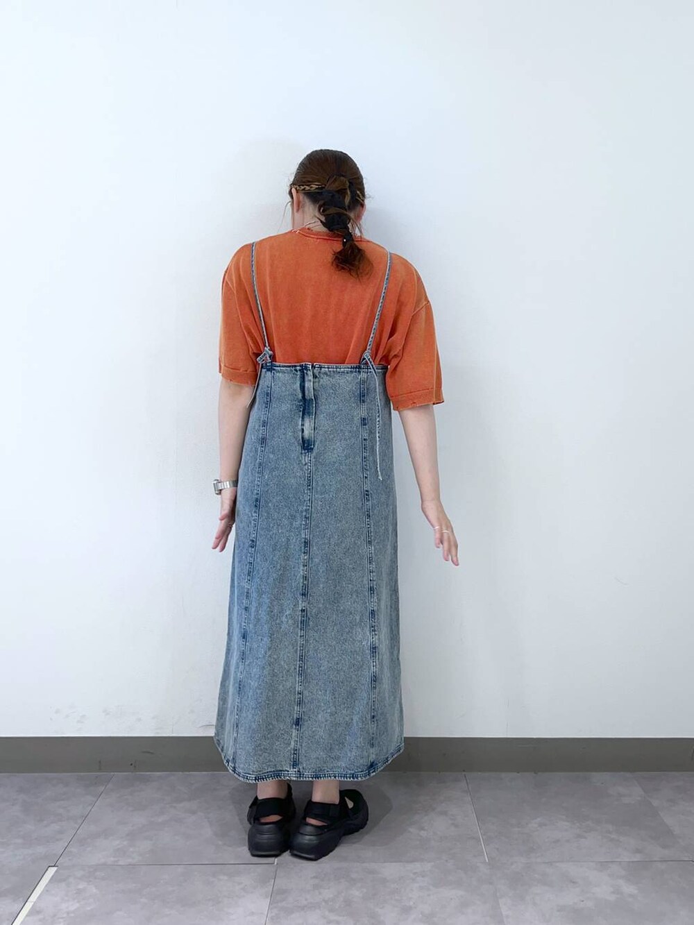 ブラック系のスニーカー、ブルー系のワンピース、オレンジ系のTシャツ/カットソーを着用したレディースの夏コーディネートの3枚目の写真