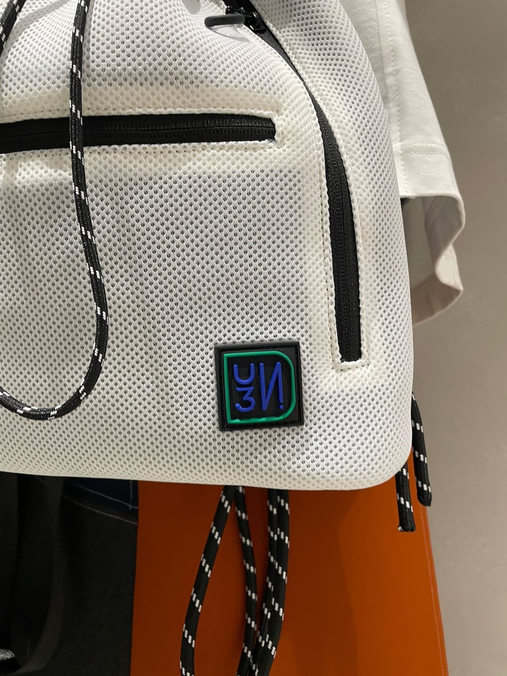 ホワイト系のTシャツ/カットソー、ホワイト系のバックパック/リュック、オレンジ系のスカートを着用したレディースの夏コーディネートの9枚目の写真