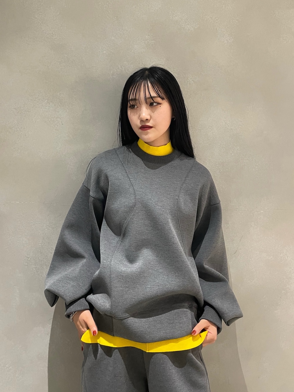 グレー系のニット/セーター、グレー系のTシャツ/カットソー、ブルー系のショルダーバッグを着用したレディースの秋コーディネートの3枚目の写真