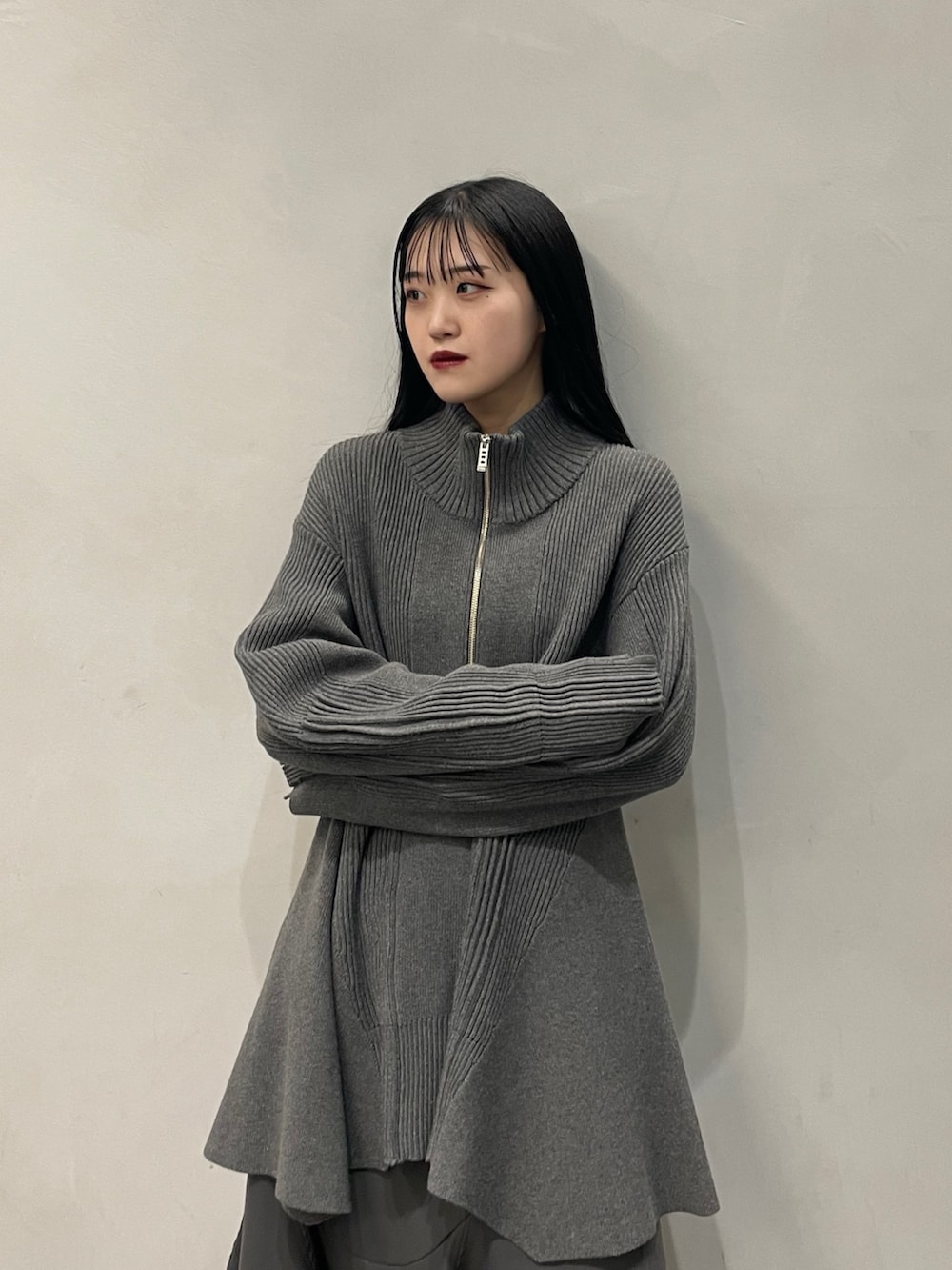 グレー系のニット/セーター、グレー系のスカート、ブラック系のブーツを着用したレディースの秋コーディネートの3枚目の写真