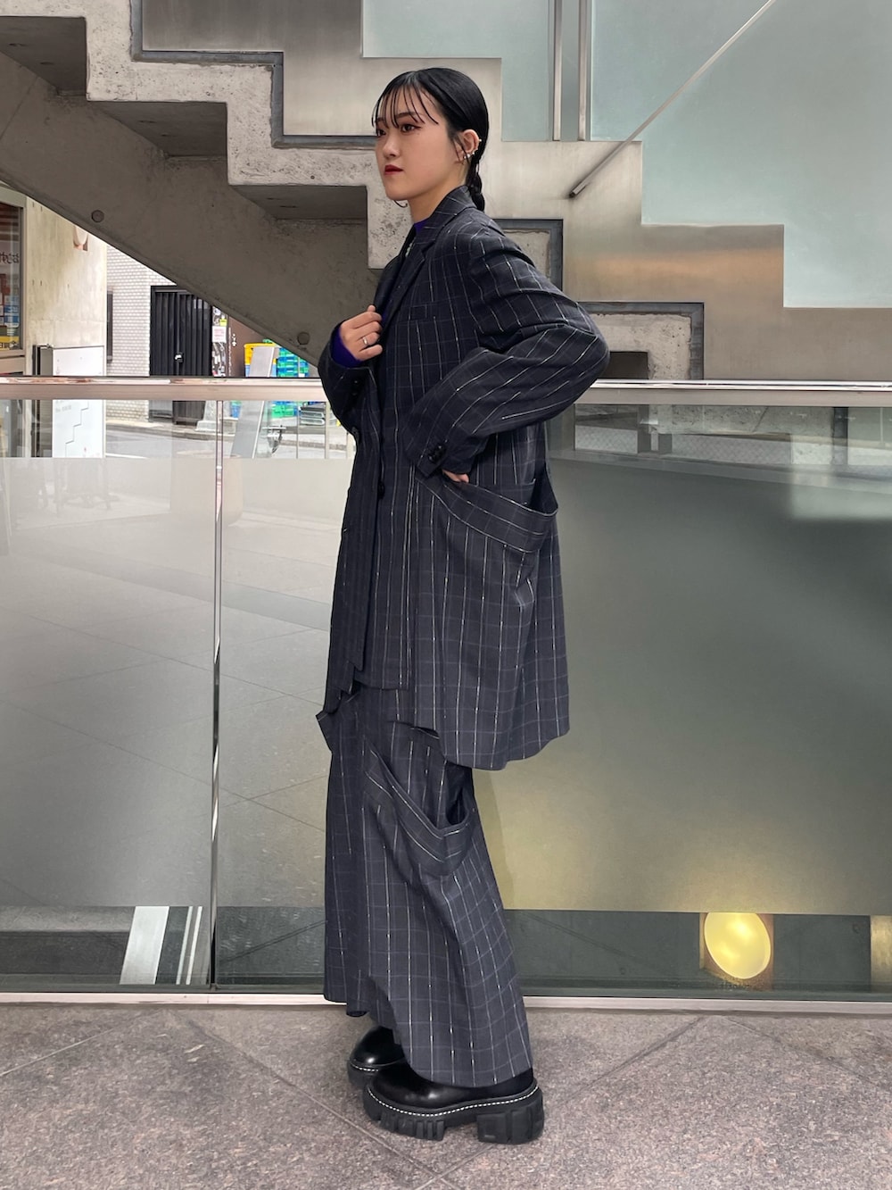 グレー系のスカート、ブラック系のブーツ、パープル系のニット/セーターを着用したレディースの秋コーディネートの2枚目の写真