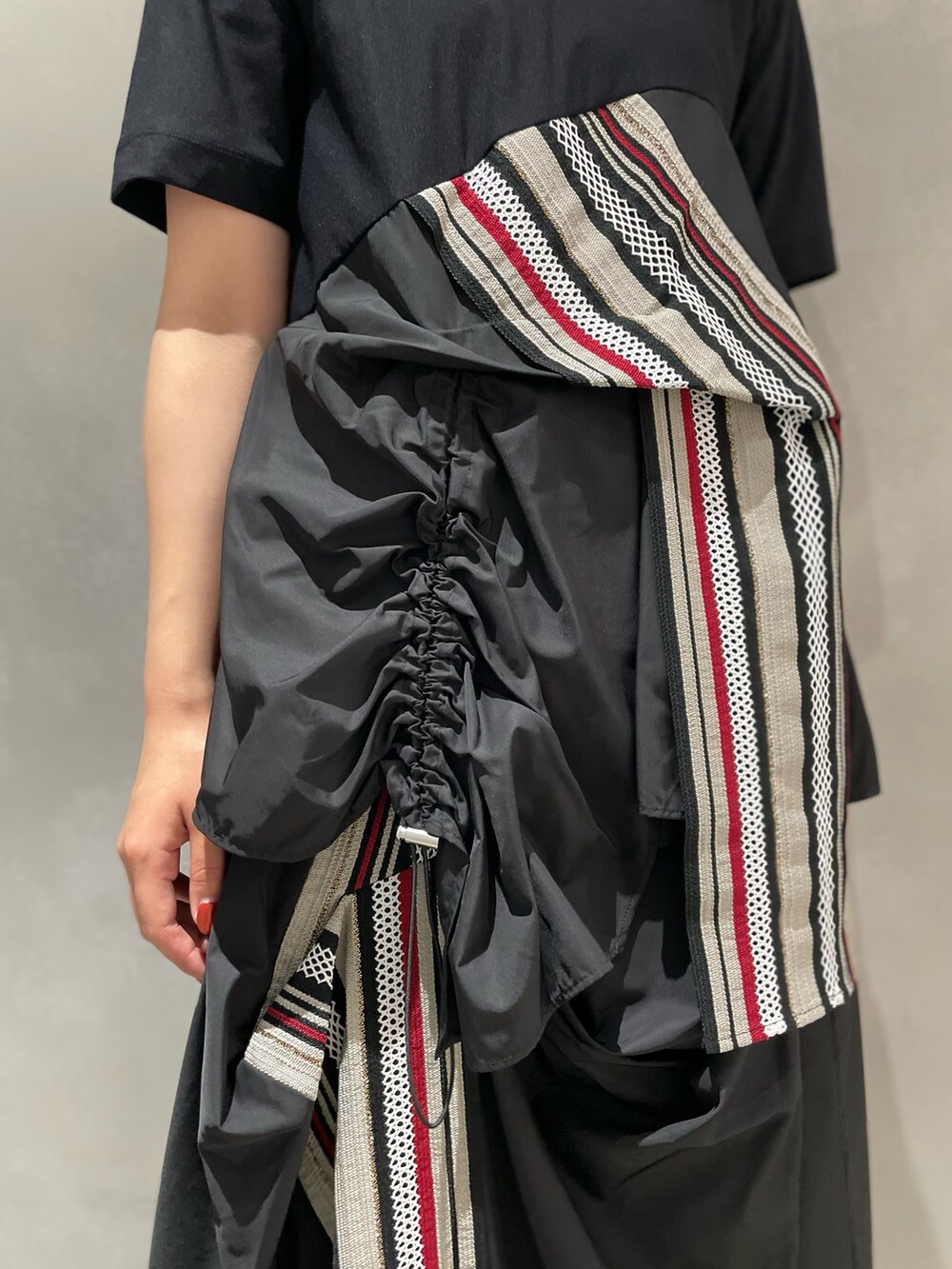 レッド系のTシャツ/カットソー、レッド系のスカート、ブラック系のブーツを着用したレディースの夏コーディネートの5枚目の写真