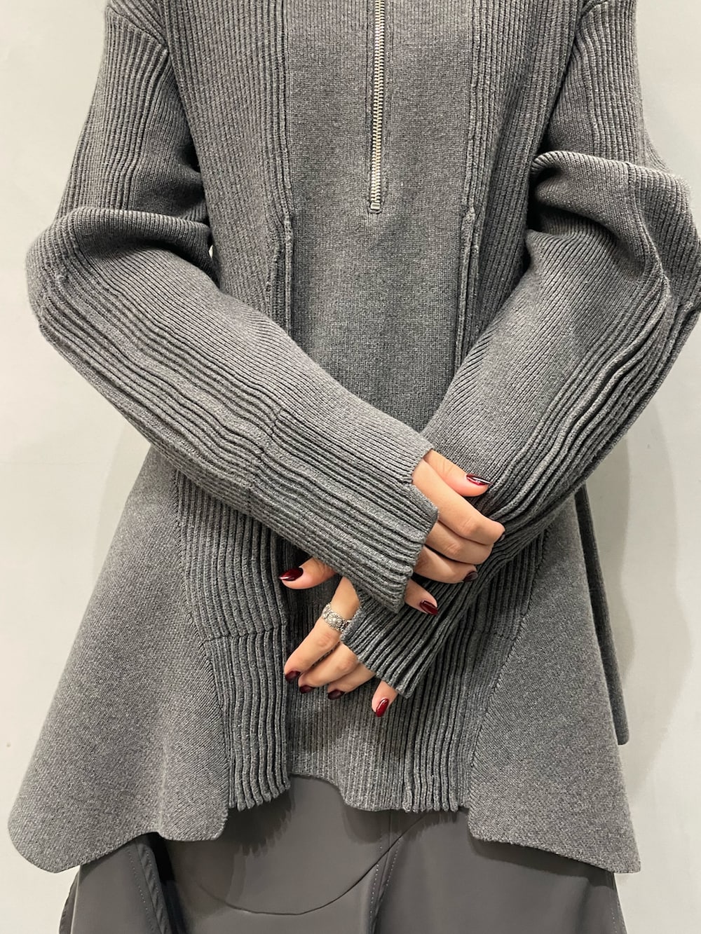 グレー系のニット/セーター、グレー系のスカート、ブラック系のブーツを着用したレディースの秋コーディネートの5枚目の写真