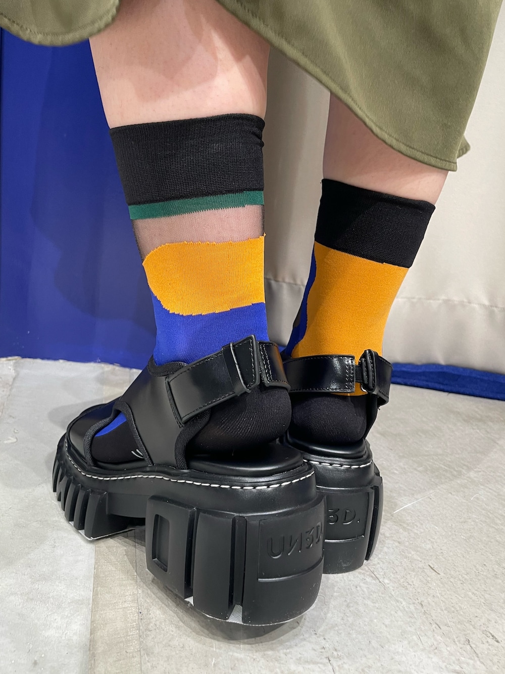 オレンジ系のニット/セーター、グリーン系のワンピース、ブラック系のサンダルを着用したレディースの春コーディネートの10枚目の写真