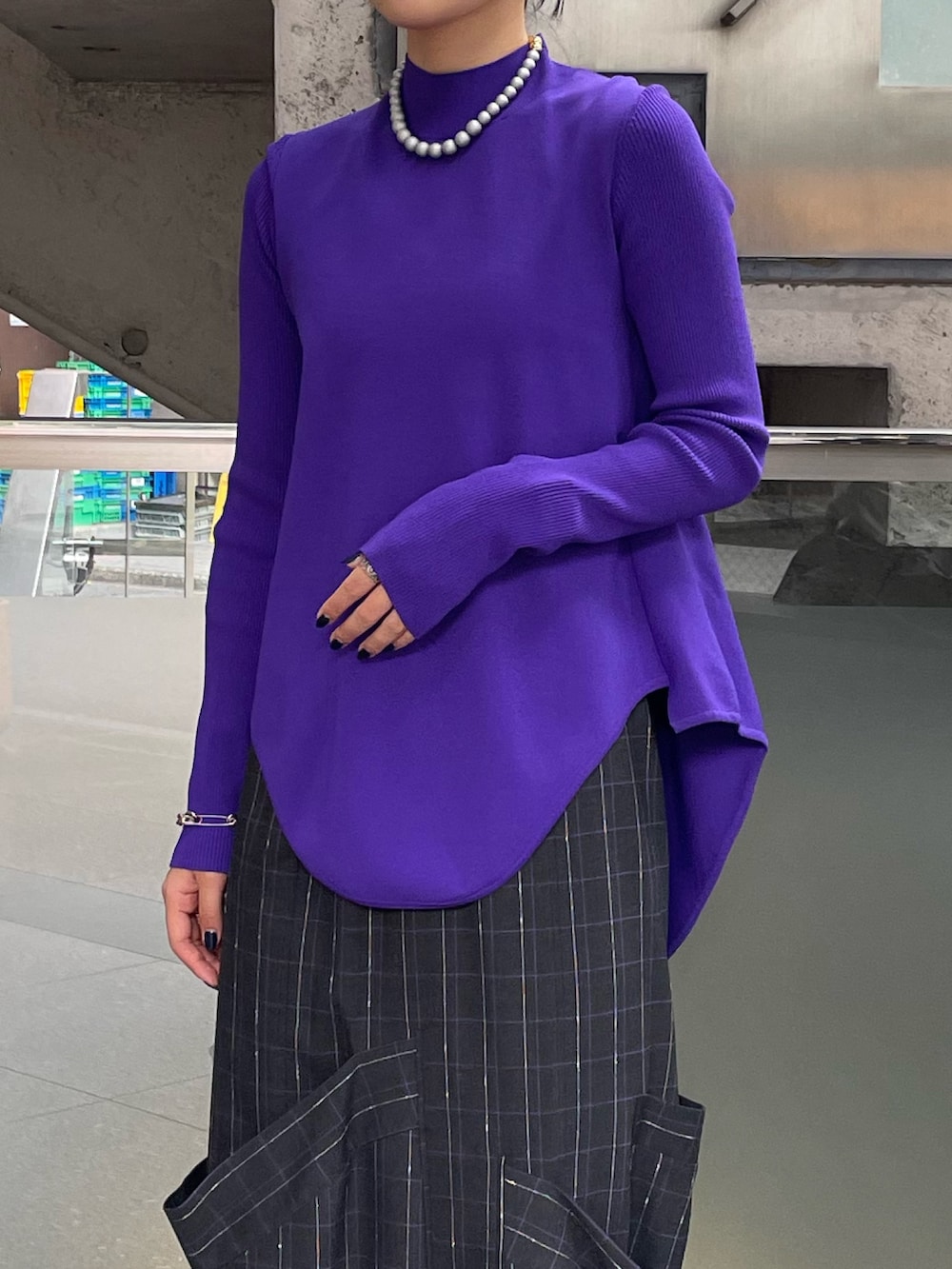 グレー系のスカート、ブラック系のブーツ、パープル系のニット/セーターを着用したレディースの秋コーディネートの6枚目の写真