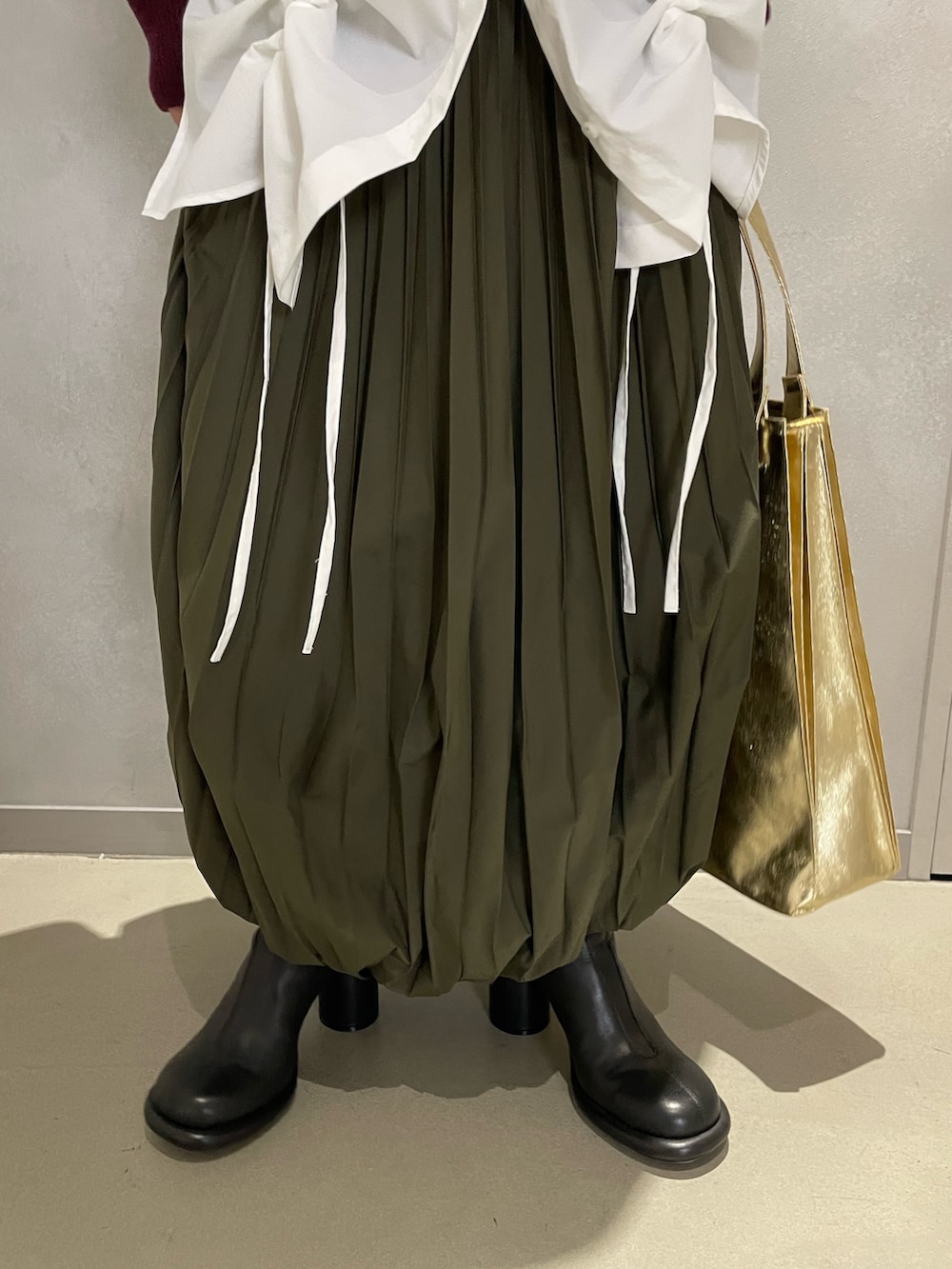 ブラウン系のニット/セーター、ホワイト系のシャツ/ブラウス、グリーン系のスカートを着用したレディースの冬コーディネートの7枚目の写真