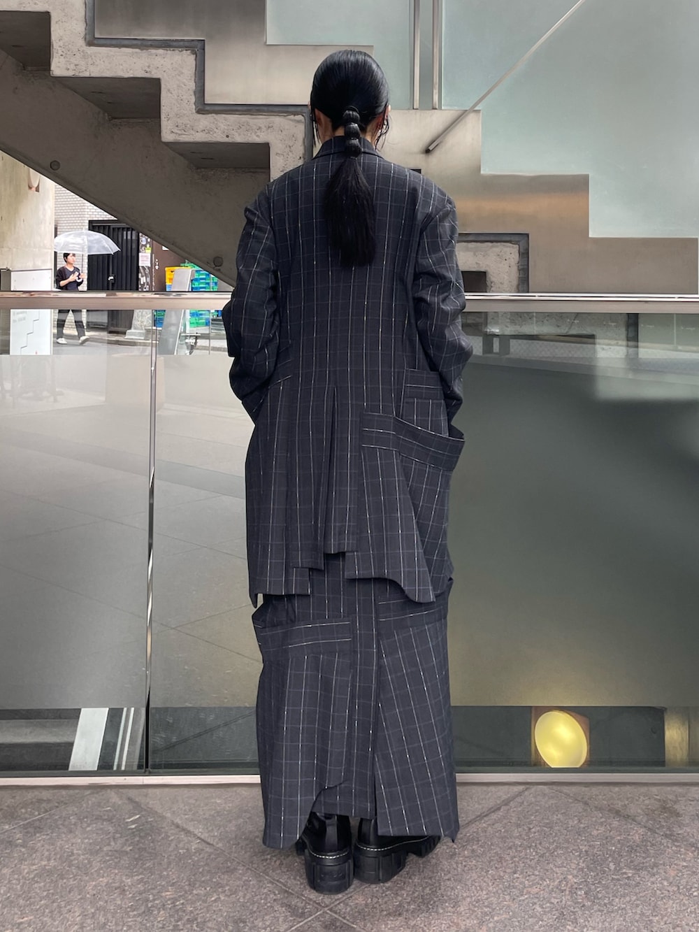 グレー系のスカート、ブラック系のブーツ、パープル系のニット/セーターを着用したレディースの秋コーディネートの3枚目の写真