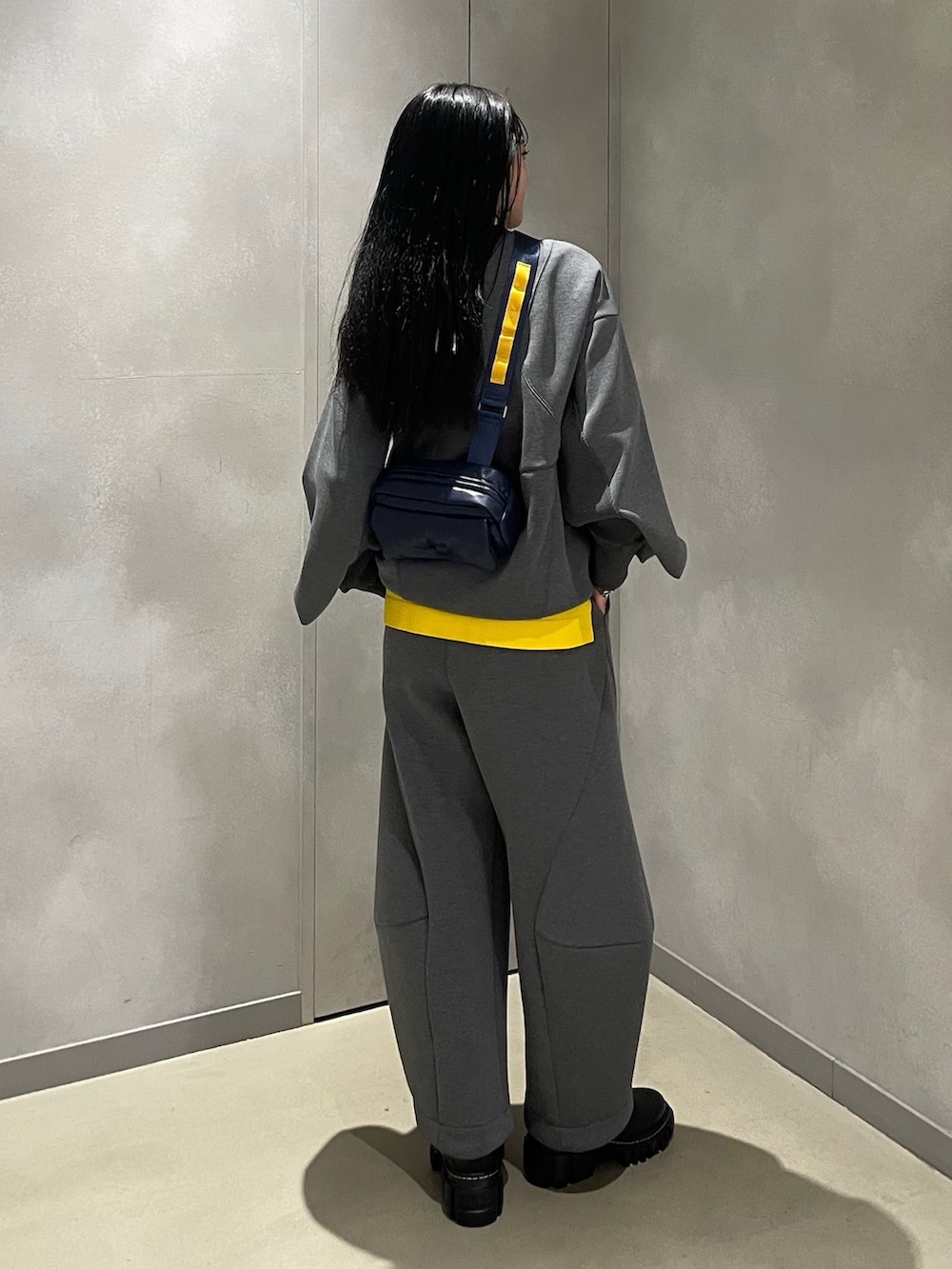 グレー系のニット/セーター、グレー系のTシャツ/カットソー、ブルー系のショルダーバッグを着用したレディースの秋コーディネートの2枚目の写真