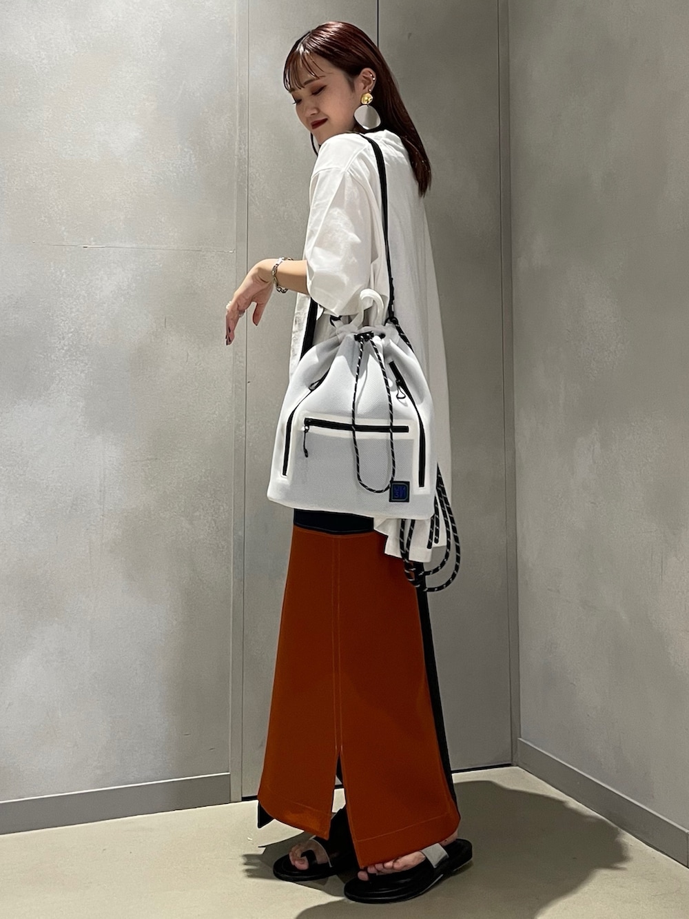 ホワイト系のTシャツ/カットソー、ホワイト系のバックパック/リュック、オレンジ系のスカートを着用したレディースの夏コーディネートの2枚目の写真