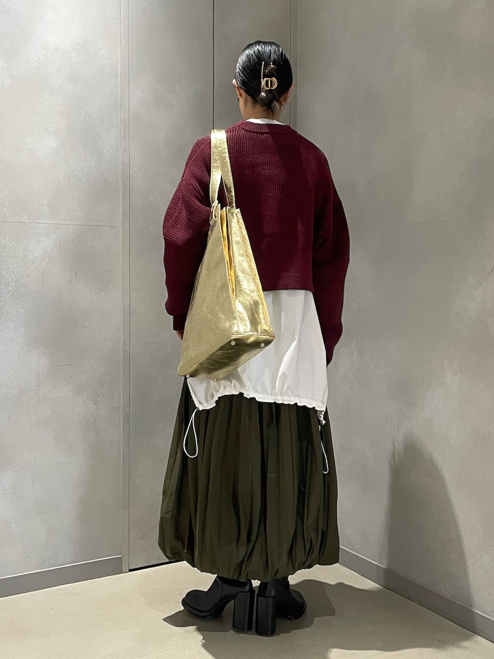 ブラウン系のニット/セーター、ホワイト系のシャツ/ブラウス、グリーン系のスカートを着用したレディースの冬コーディネートの3枚目の写真