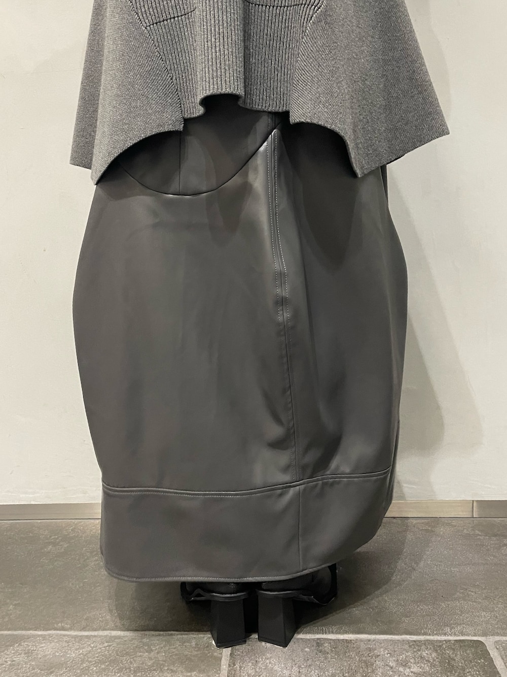 グレー系のニット/セーター、グレー系のスカート、ブラック系のブーツを着用したレディースの秋コーディネートの7枚目の写真