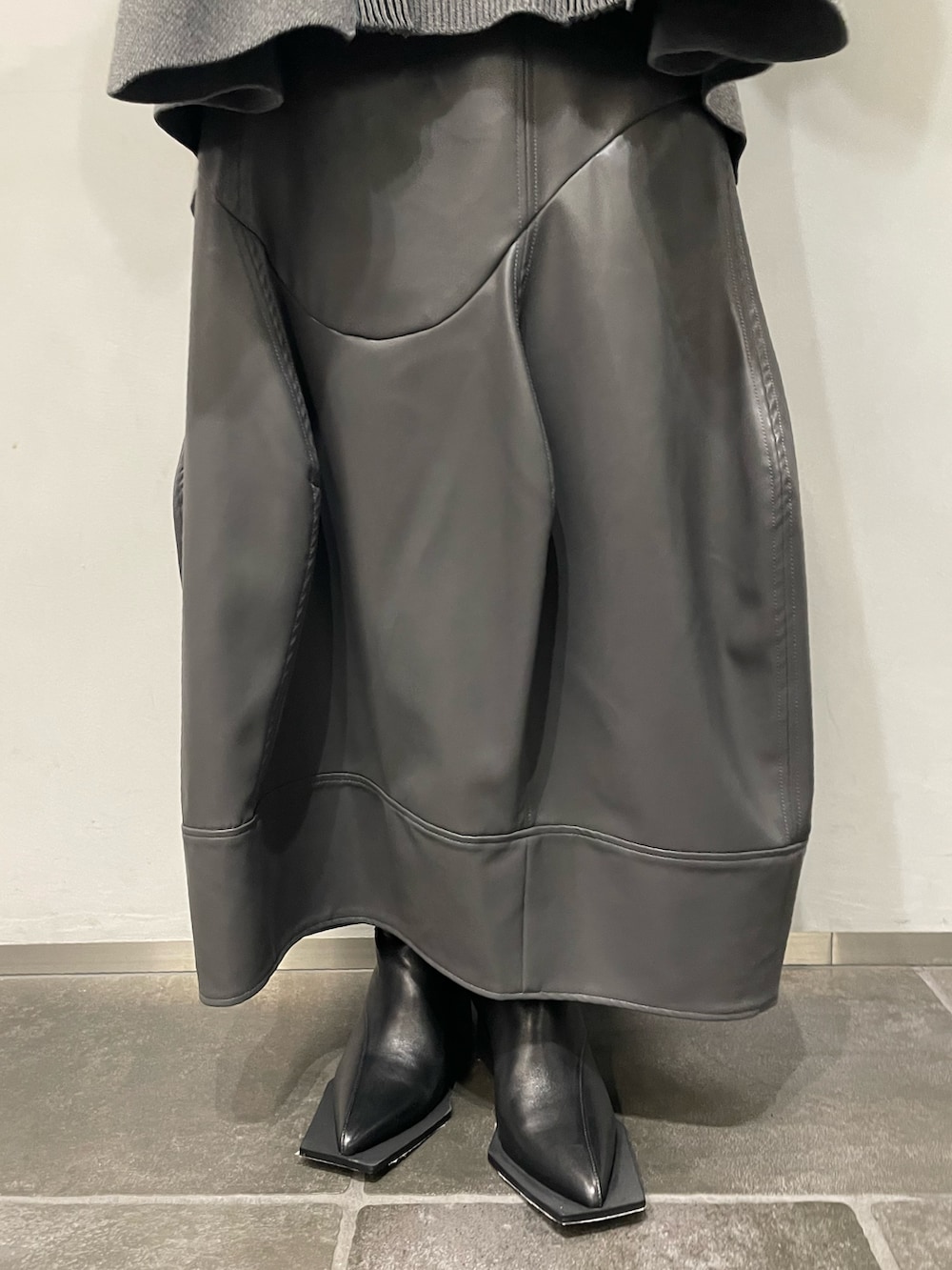 グレー系のニット/セーター、グレー系のスカート、ブラック系のブーツを着用したレディースの秋コーディネートの6枚目の写真