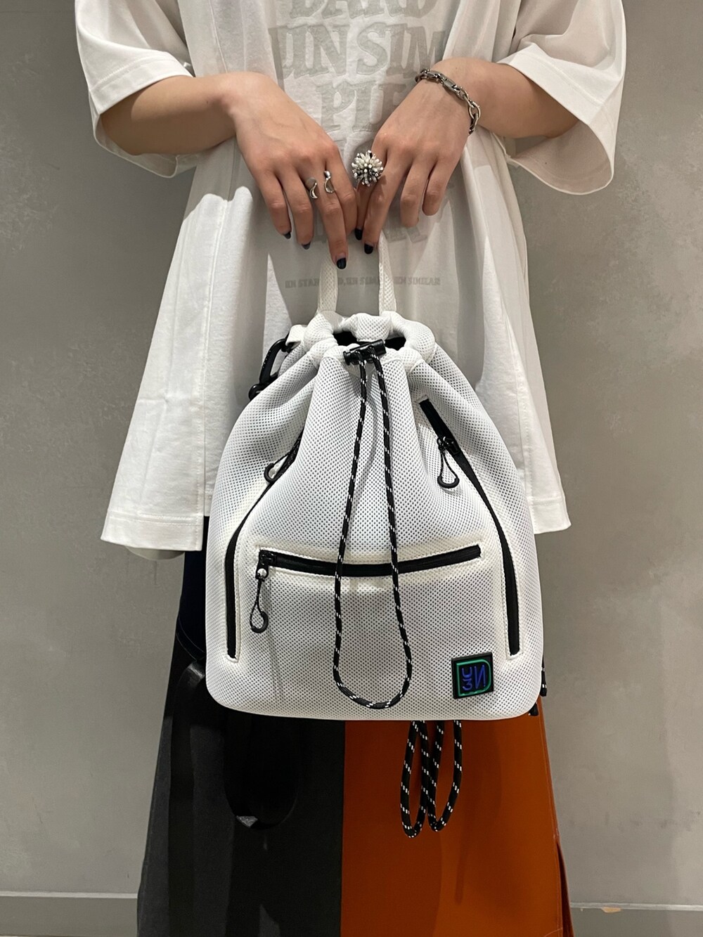 ホワイト系のTシャツ/カットソー、ホワイト系のバックパック/リュック、オレンジ系のスカートを着用したレディースの夏コーディネートの8枚目の写真