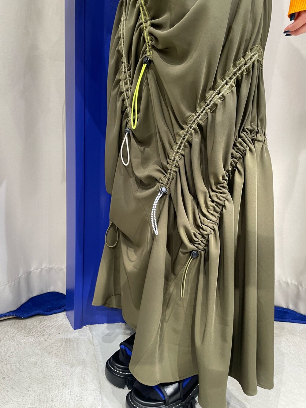 オレンジ系のニット/セーター、グリーン系のワンピース、ブラック系のサンダルを着用したレディースの春コーディネートの8枚目の写真